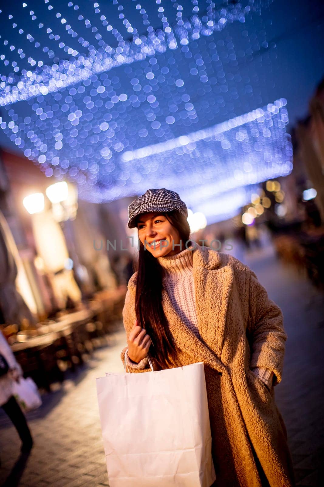 Beautiful young woman on the street at cold Christmas night