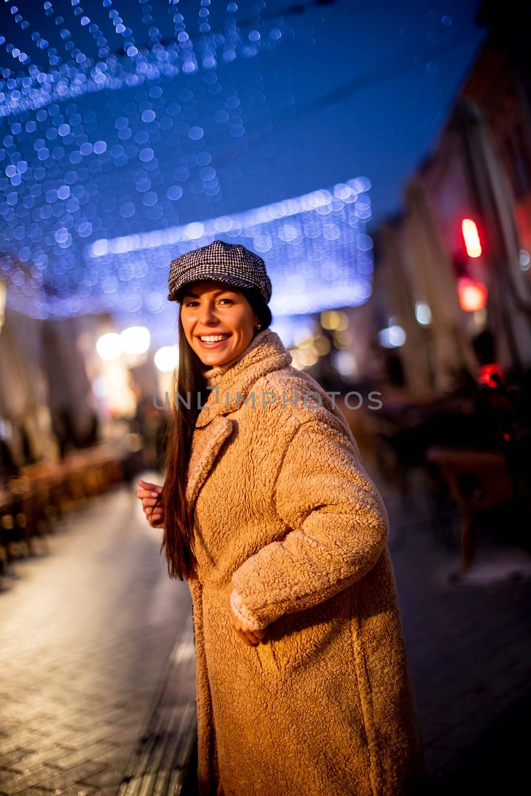 Beautiful young woman on the street at cold Christmas night