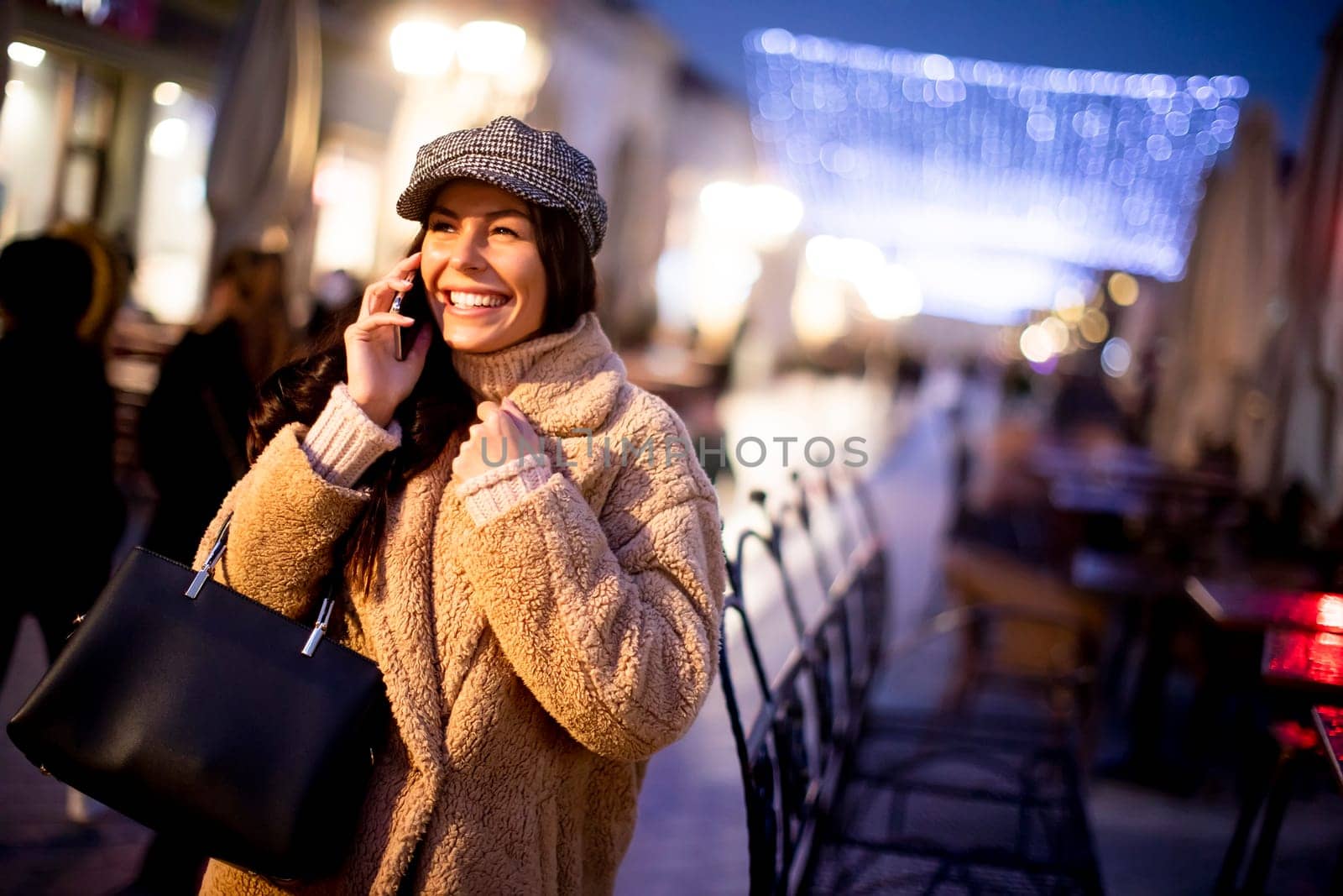 Beautiful young woman using her mobile phone in the street at Christmas time