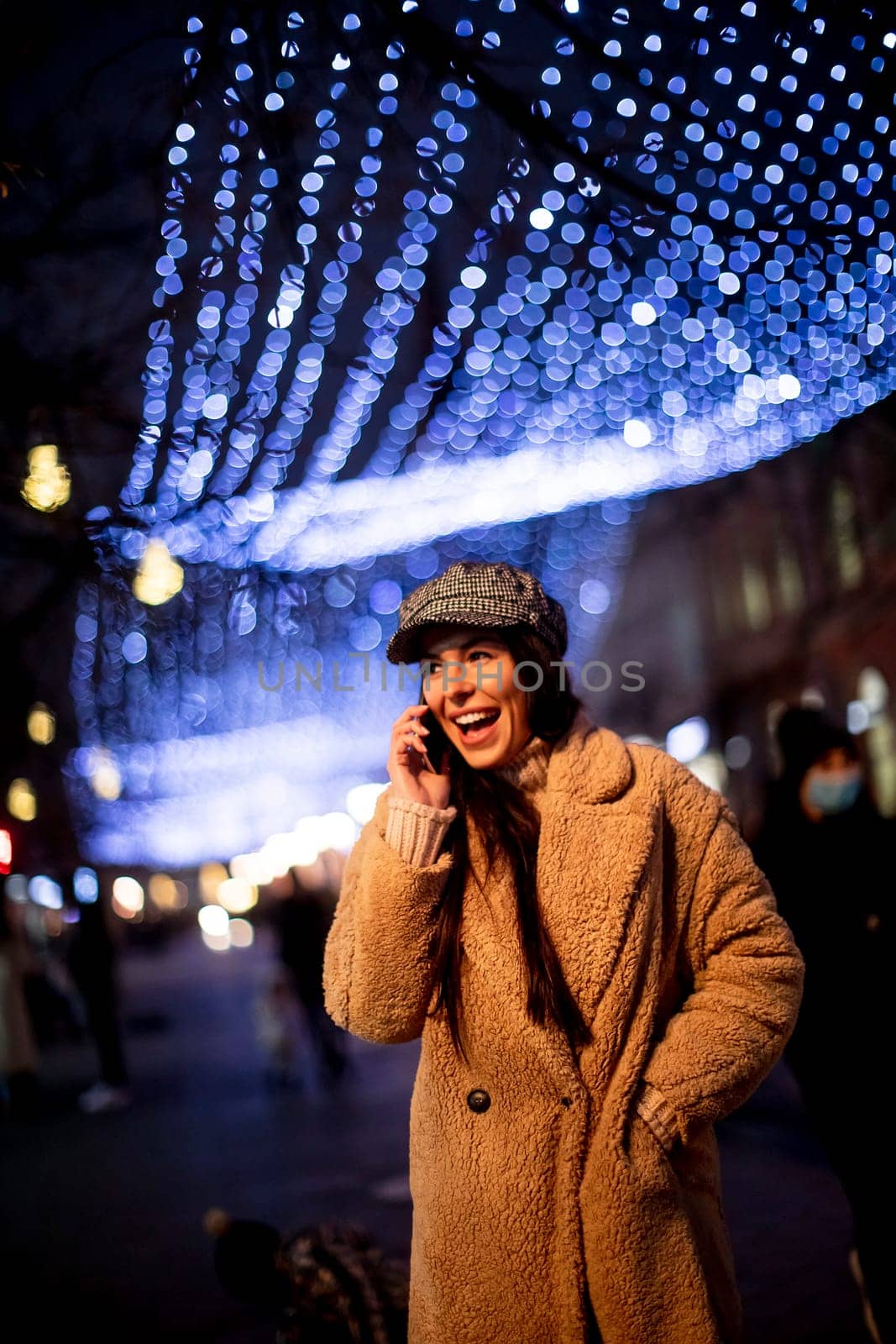 Beautiful young woman using her mobile phone in the street at Christmas time