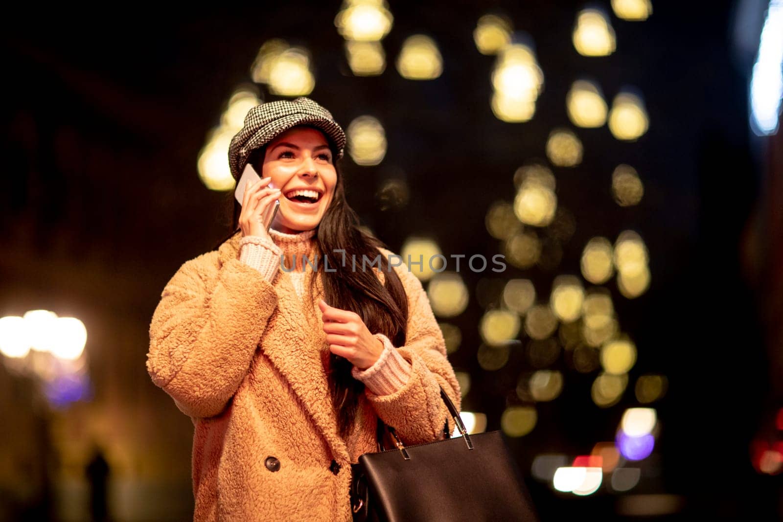 Beautiful young woman using her mobile phone in the street at Christmas time