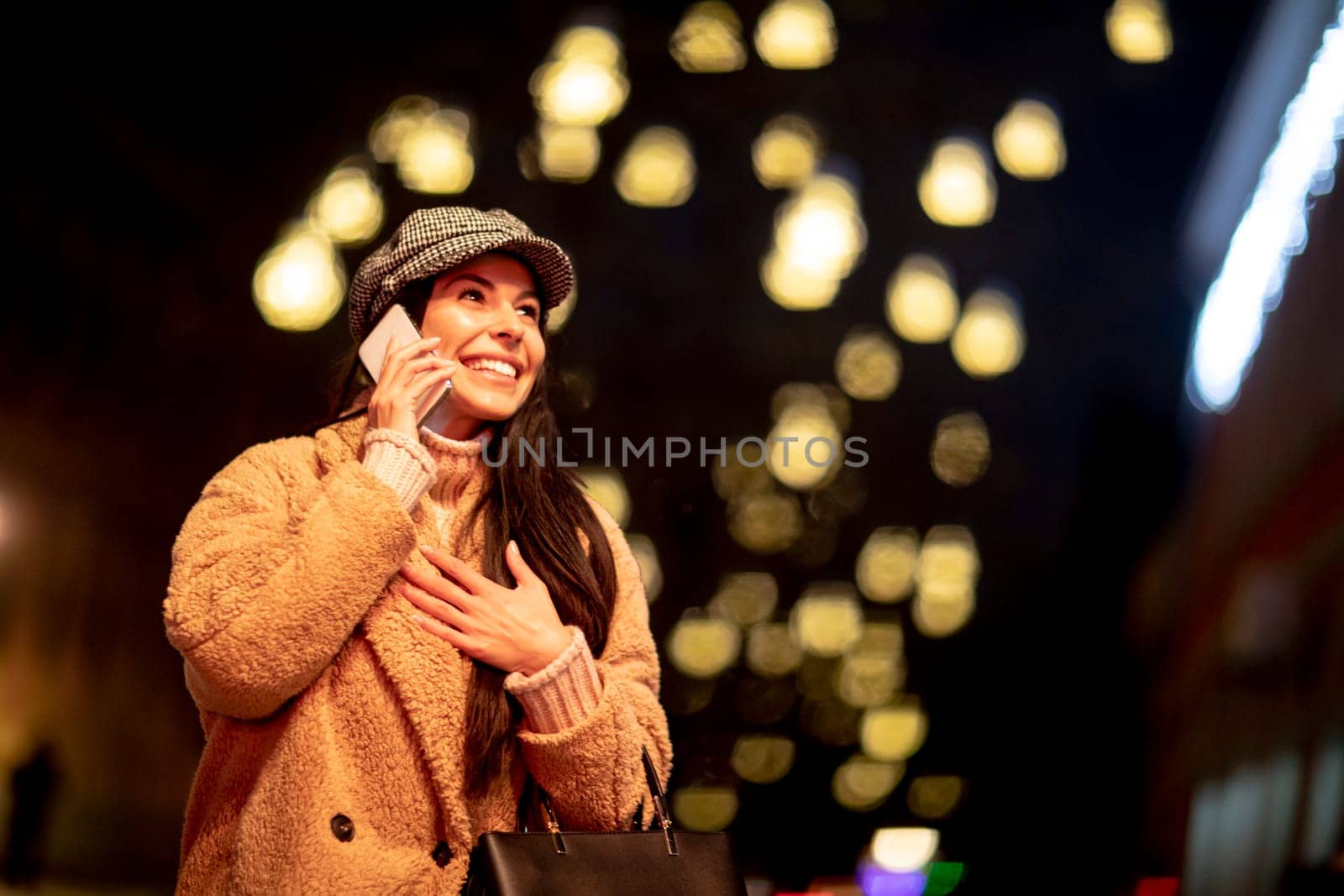 Beautiful young woman using her mobile phone in the street at Christmas time