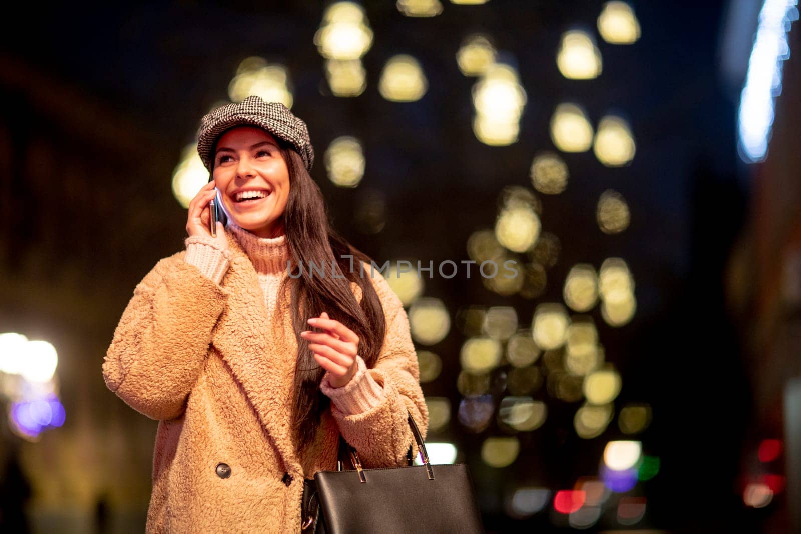 Beautiful young woman using her mobile phone in the street at Christmas time