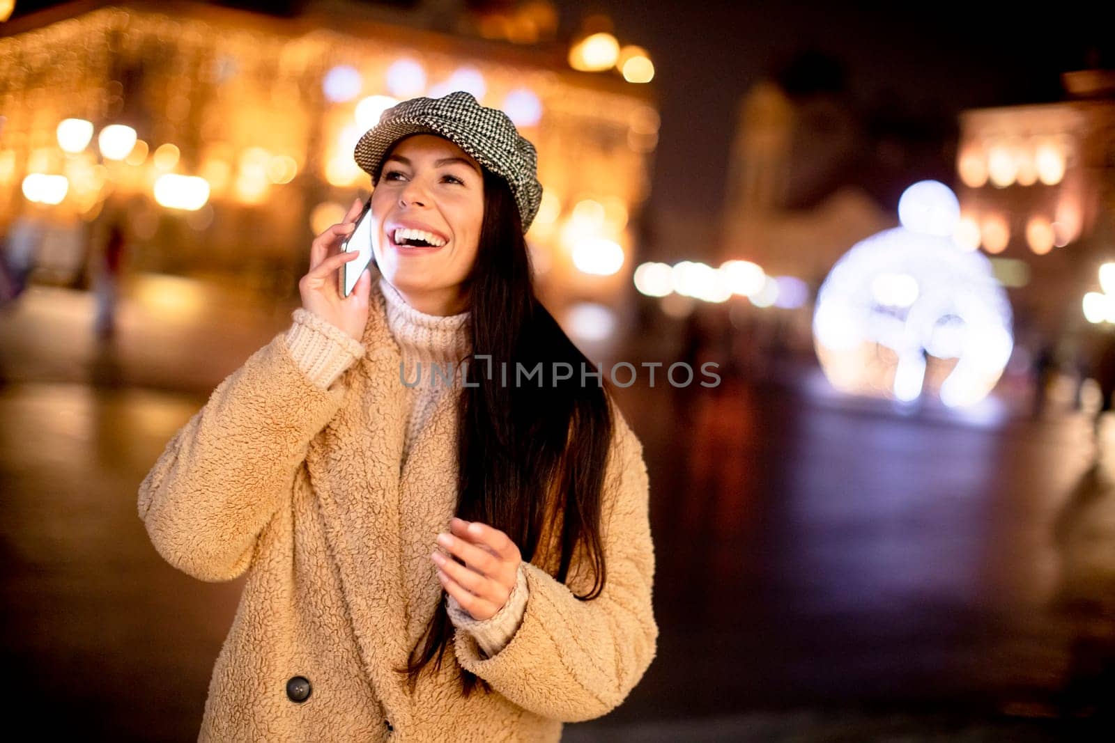 Beautiful young woman using her mobile phone in the street at Christmas time