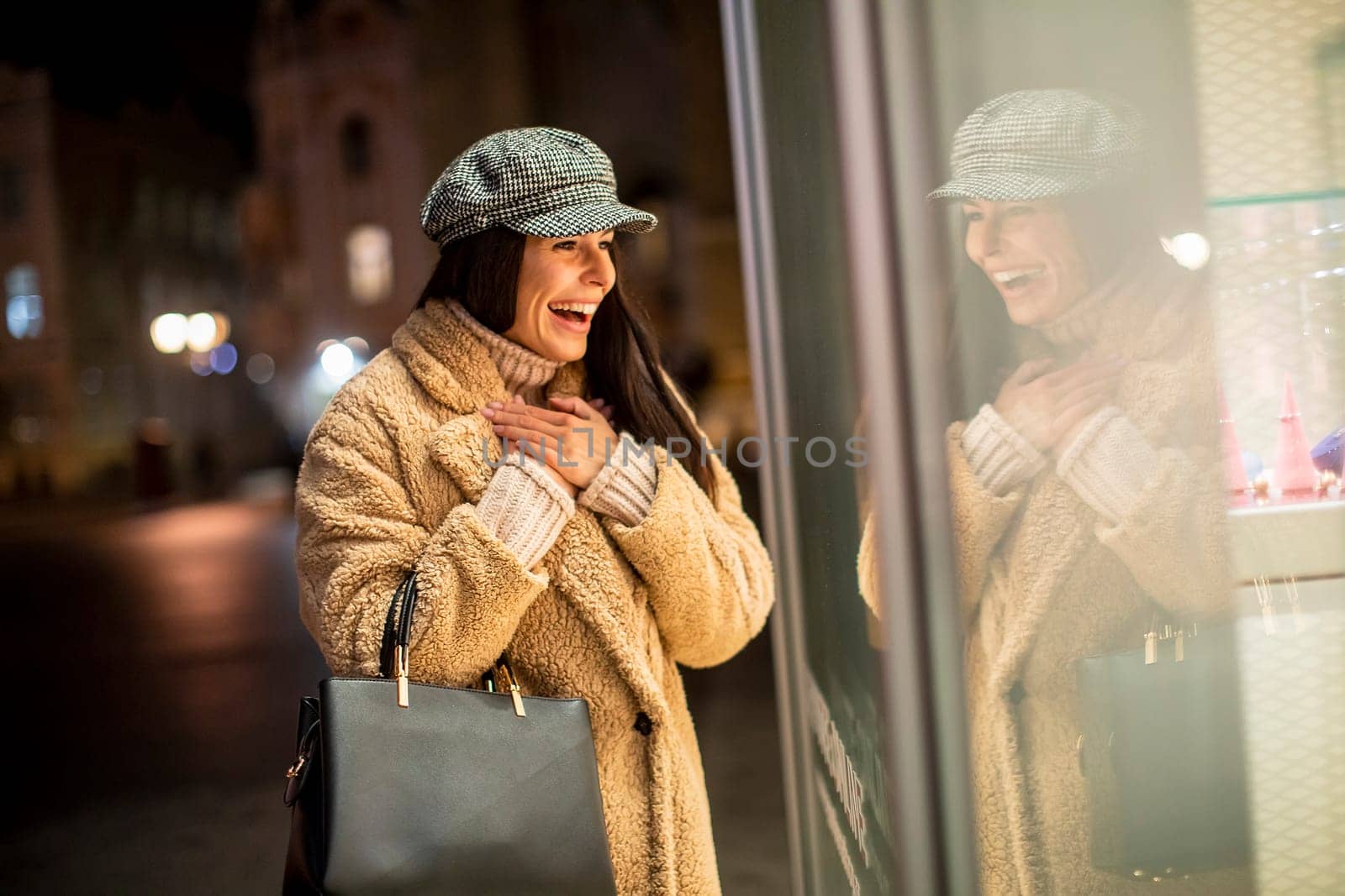 Pretty young woman by the shop window at Christmas time