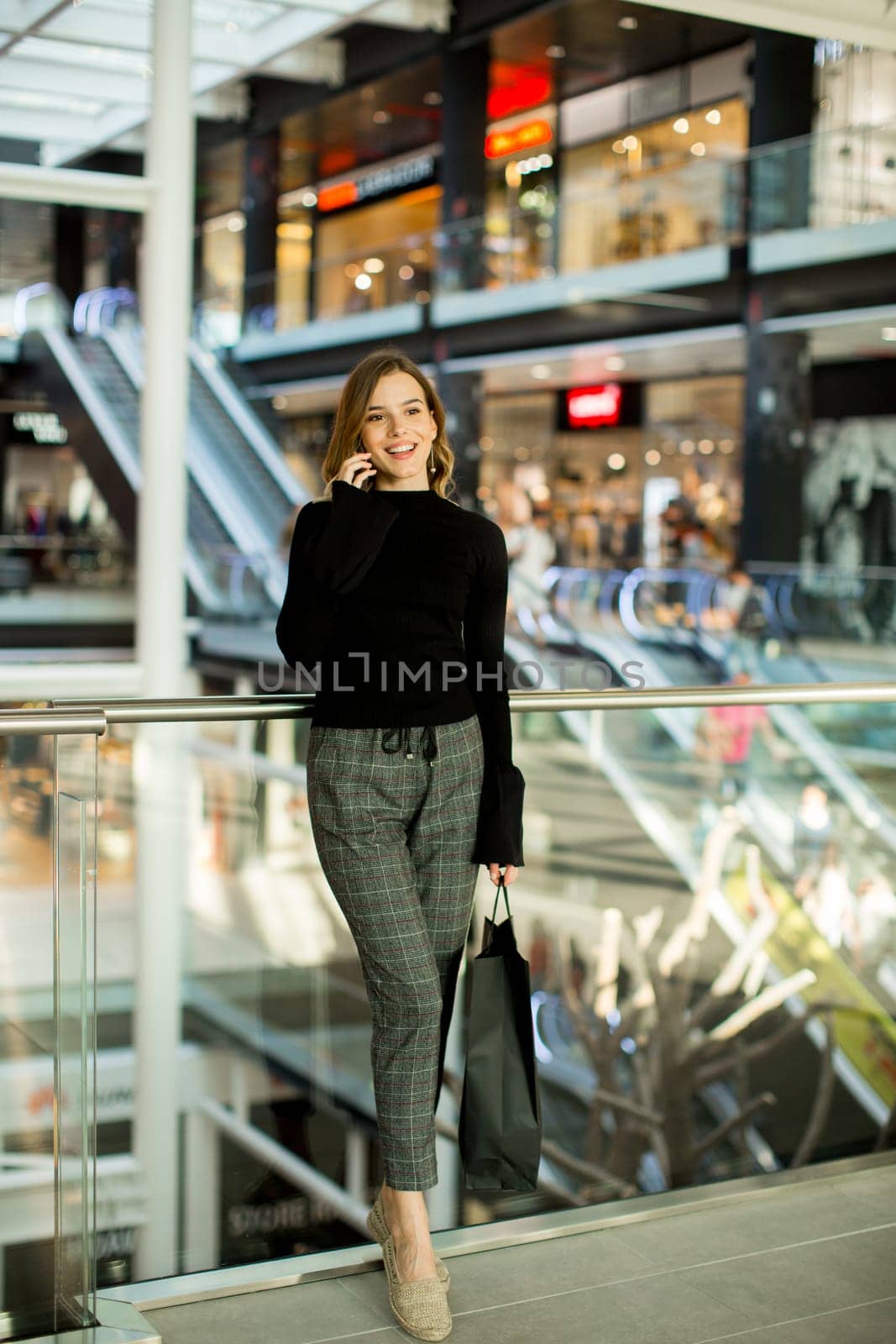 Young woman standing in shopping mall talking over mobile phone