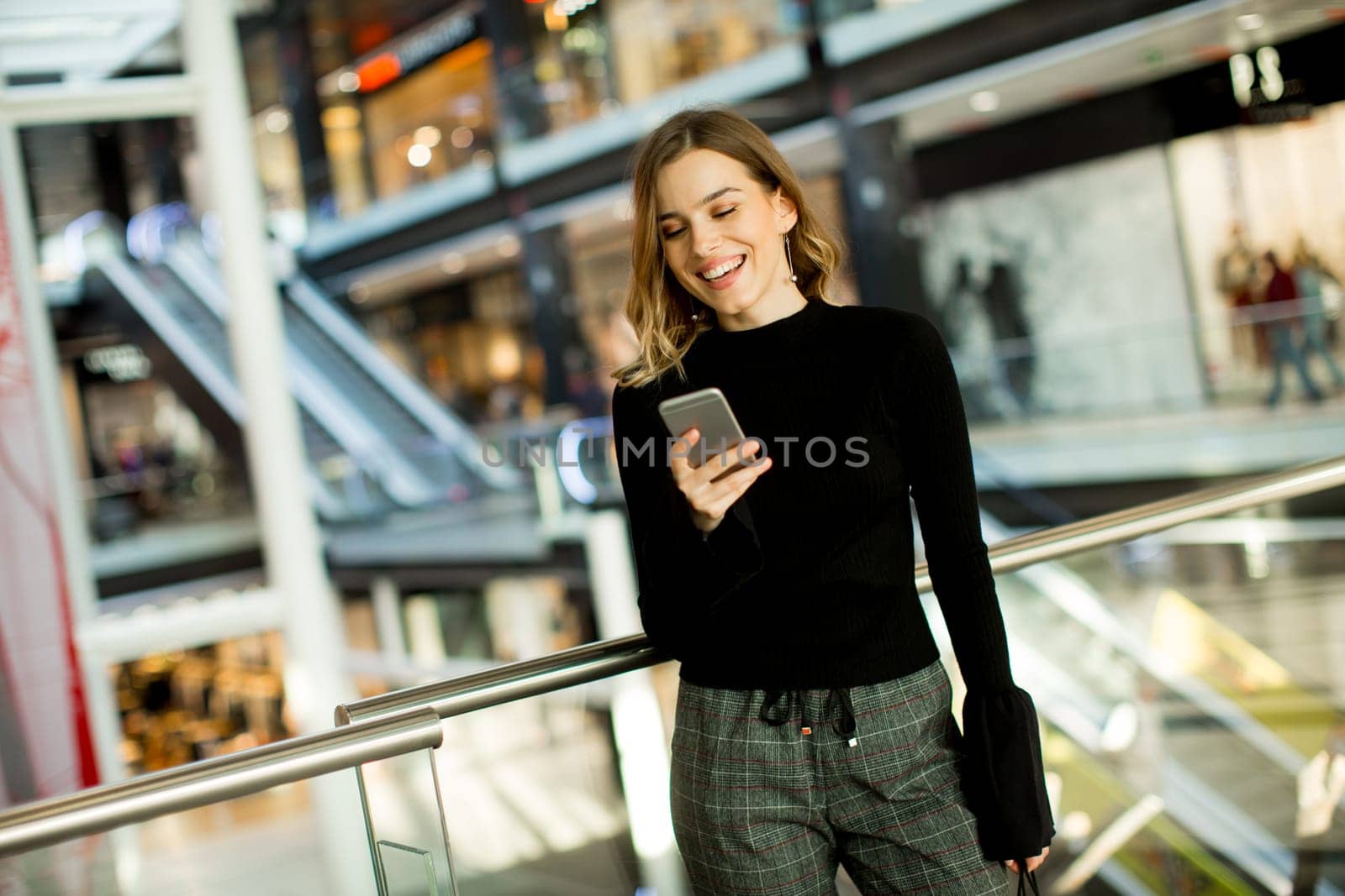 Portrait of lovely young woman looking on mobile phone in shopping center