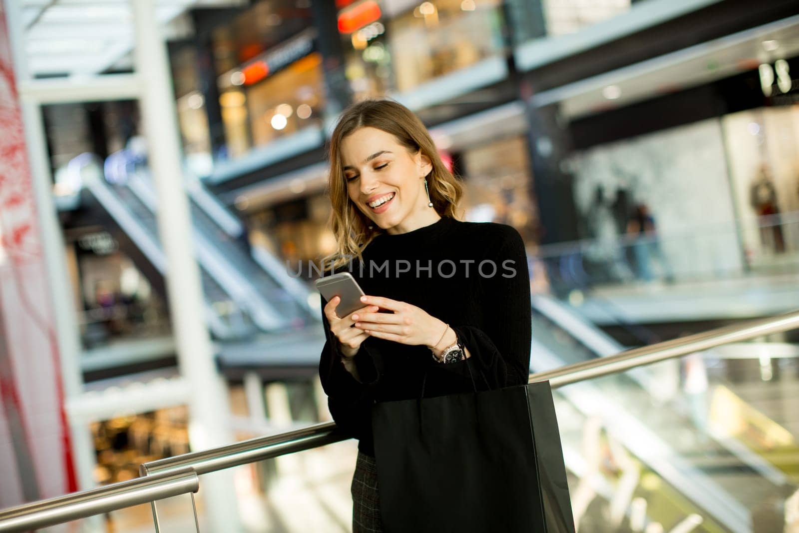 Portrait of lovely young woman looking on mobile phone in shopping center