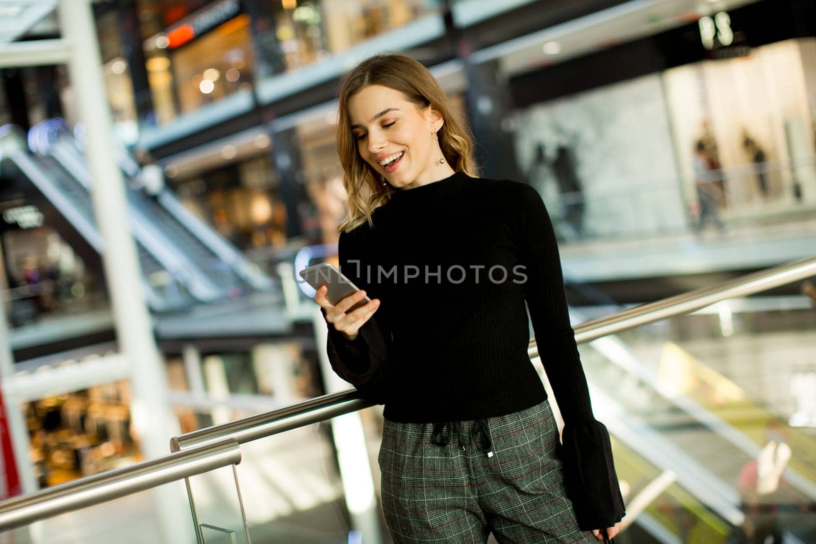 Portrait of lovely young woman looking on mobile phone in shopping center