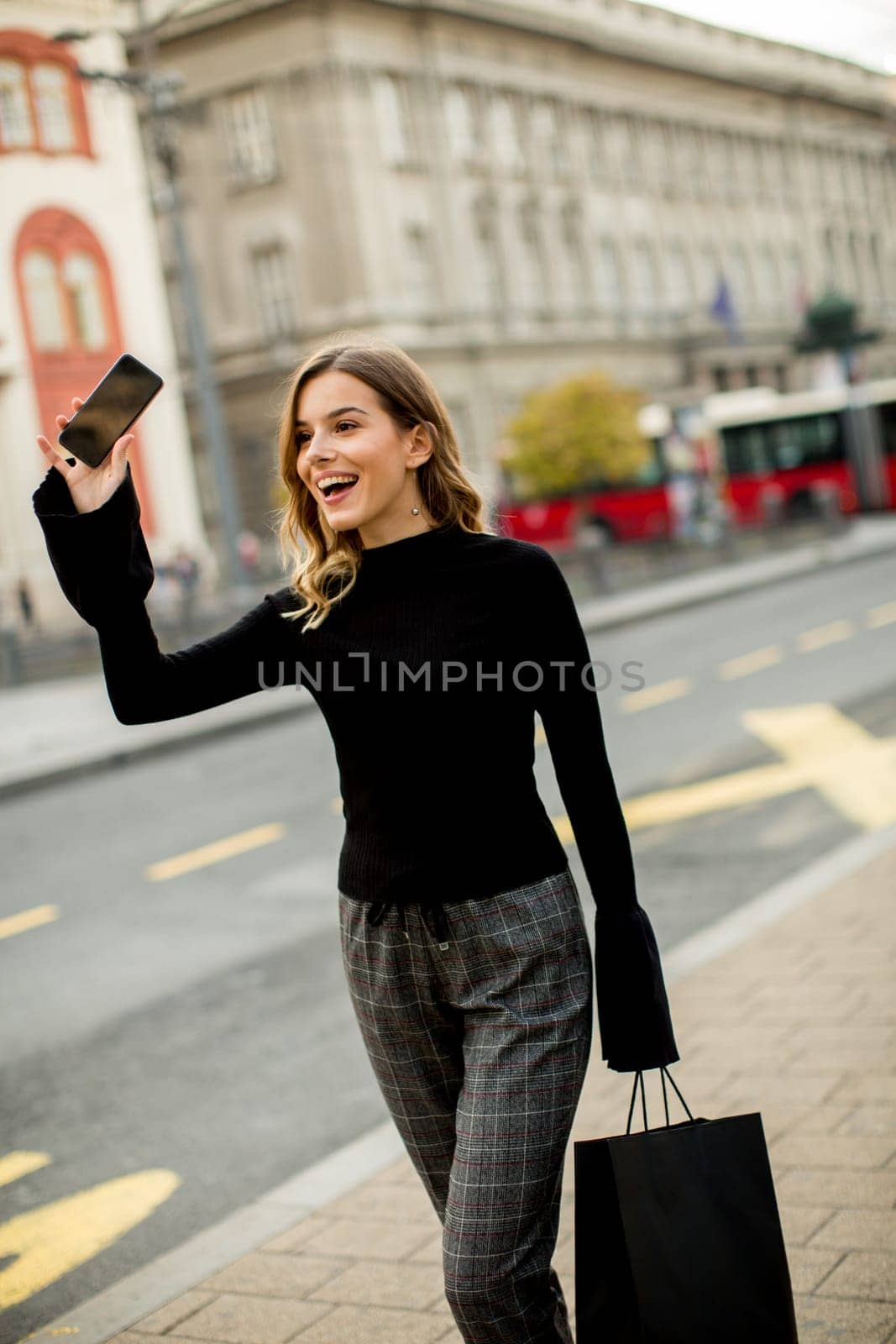 Portrait of young woman waiting for taxi or bus on the street in the city