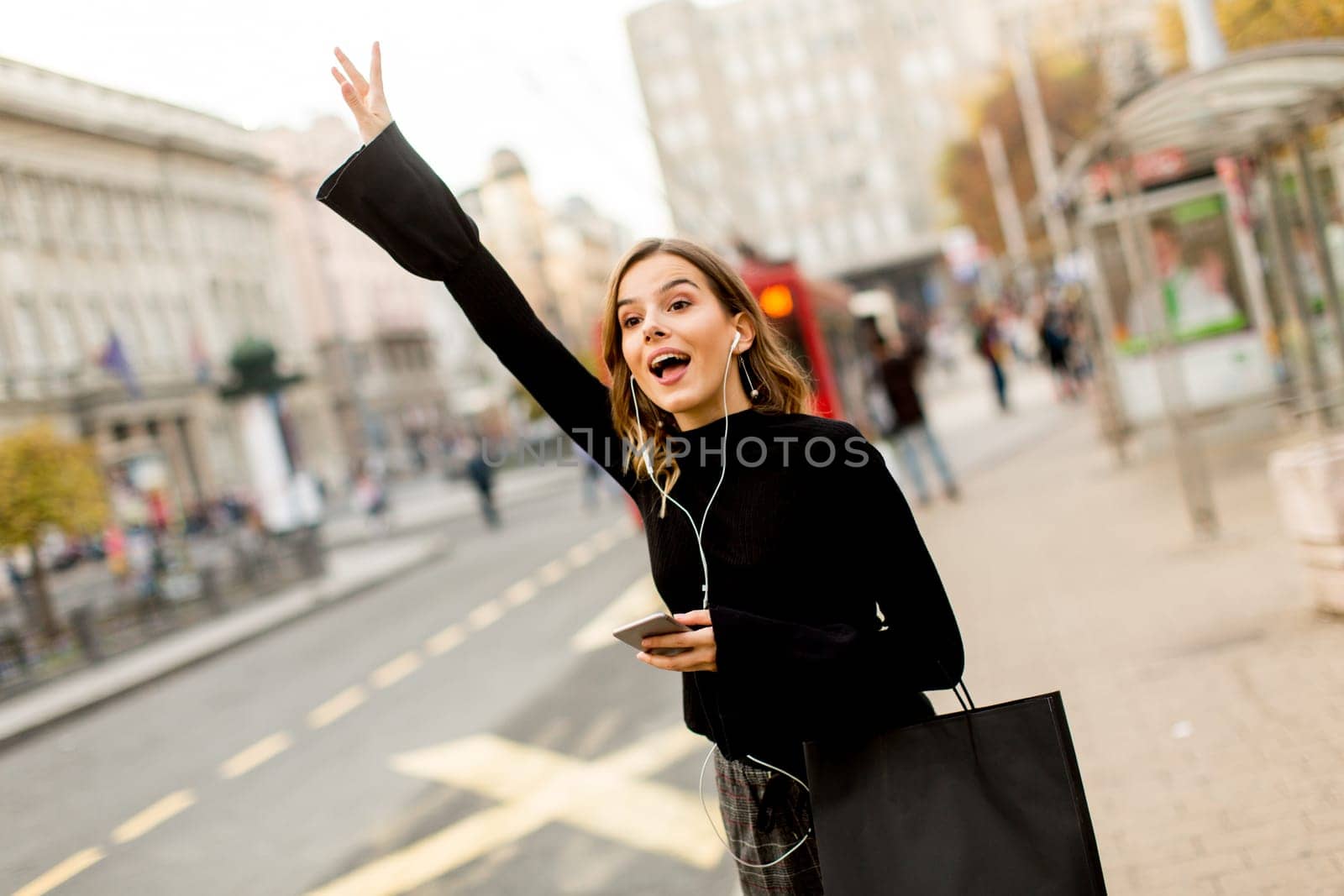 Portrait of young woman waiting for taxi or bus on the street in the city