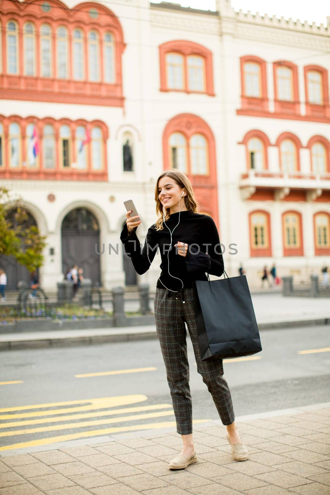 Young woman on the street with mobile phone and listening music