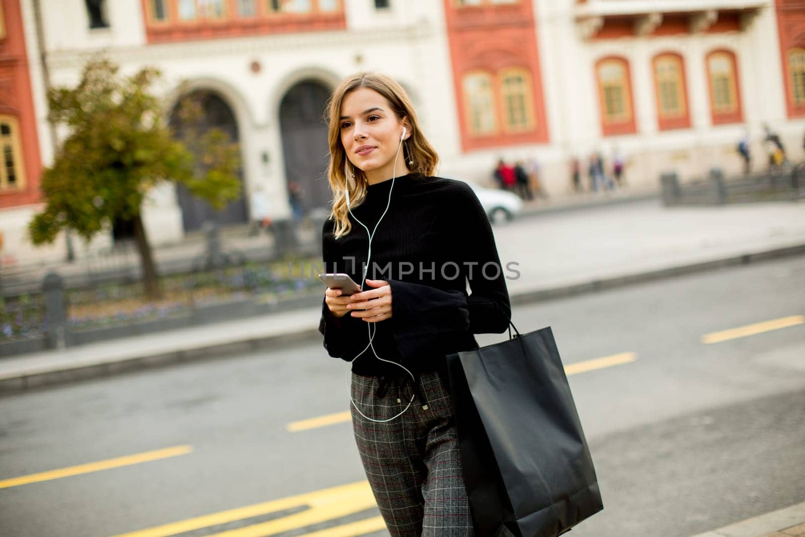 Young woman waiting for taxi or bus on the street in the city