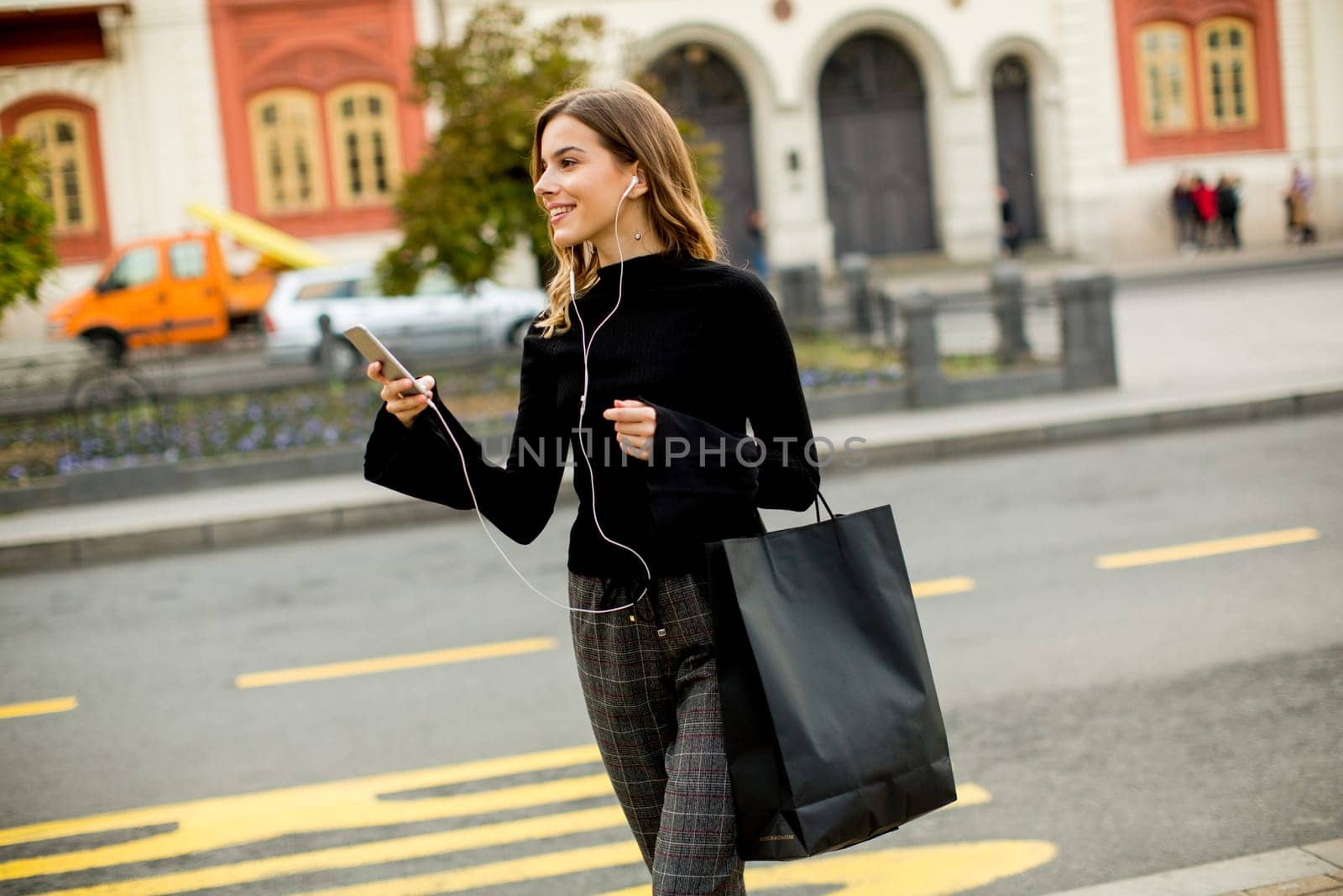 Young woman waiting for taxi or bus on the street in the city