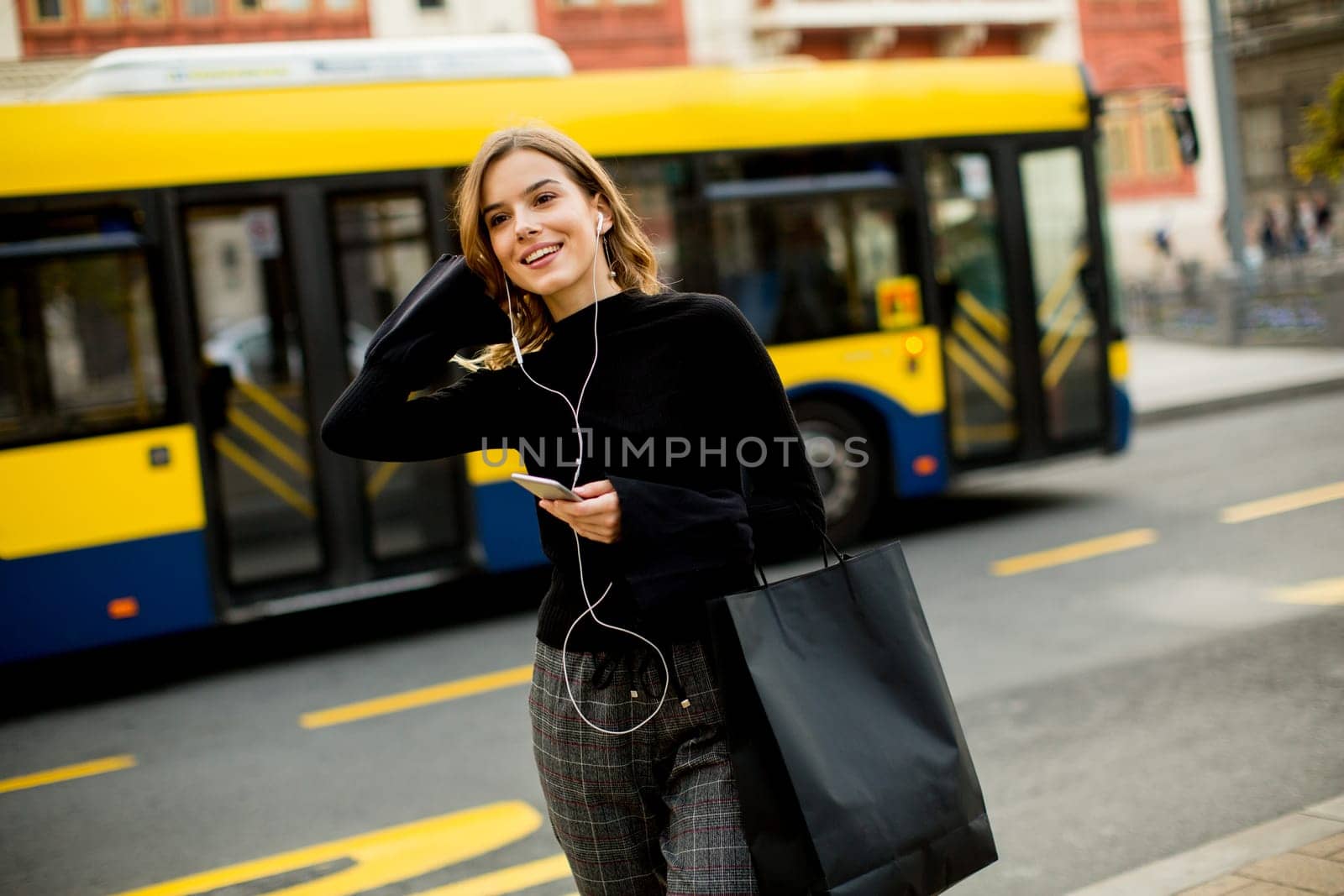 Young woman waiting for taxi or bus on the street in the city