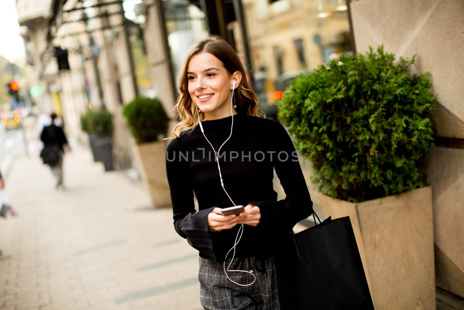 Young woman on the street with mobile phone and listening music