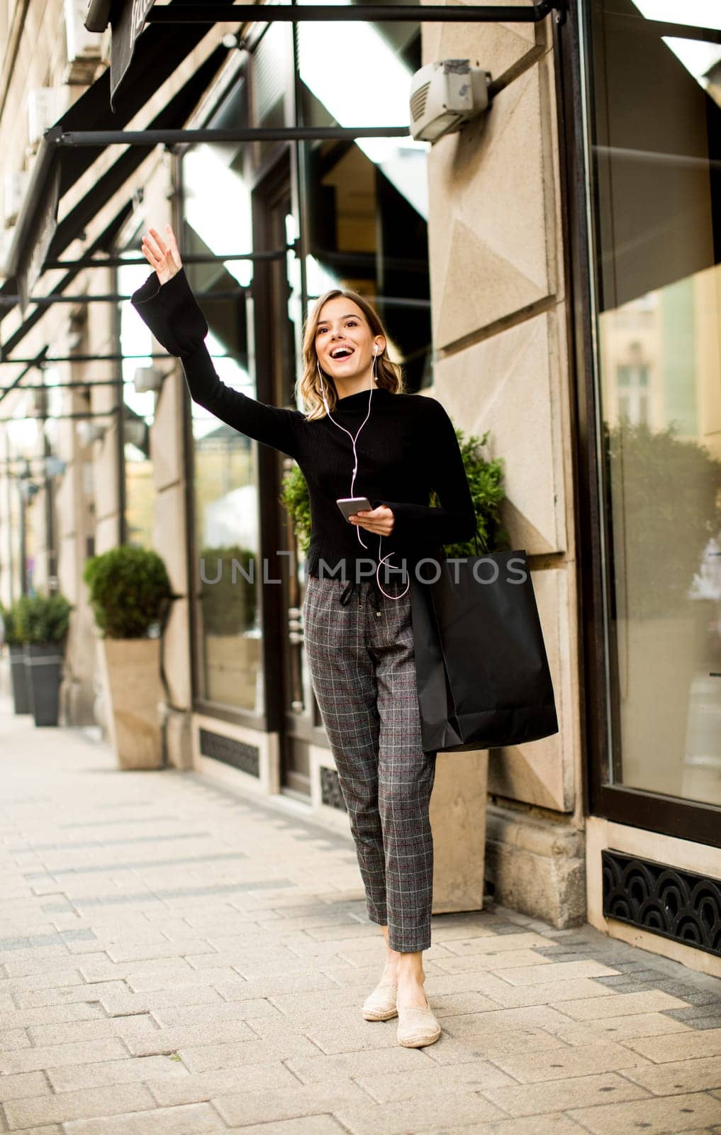 Young woman on the street with mobile phone and listening music