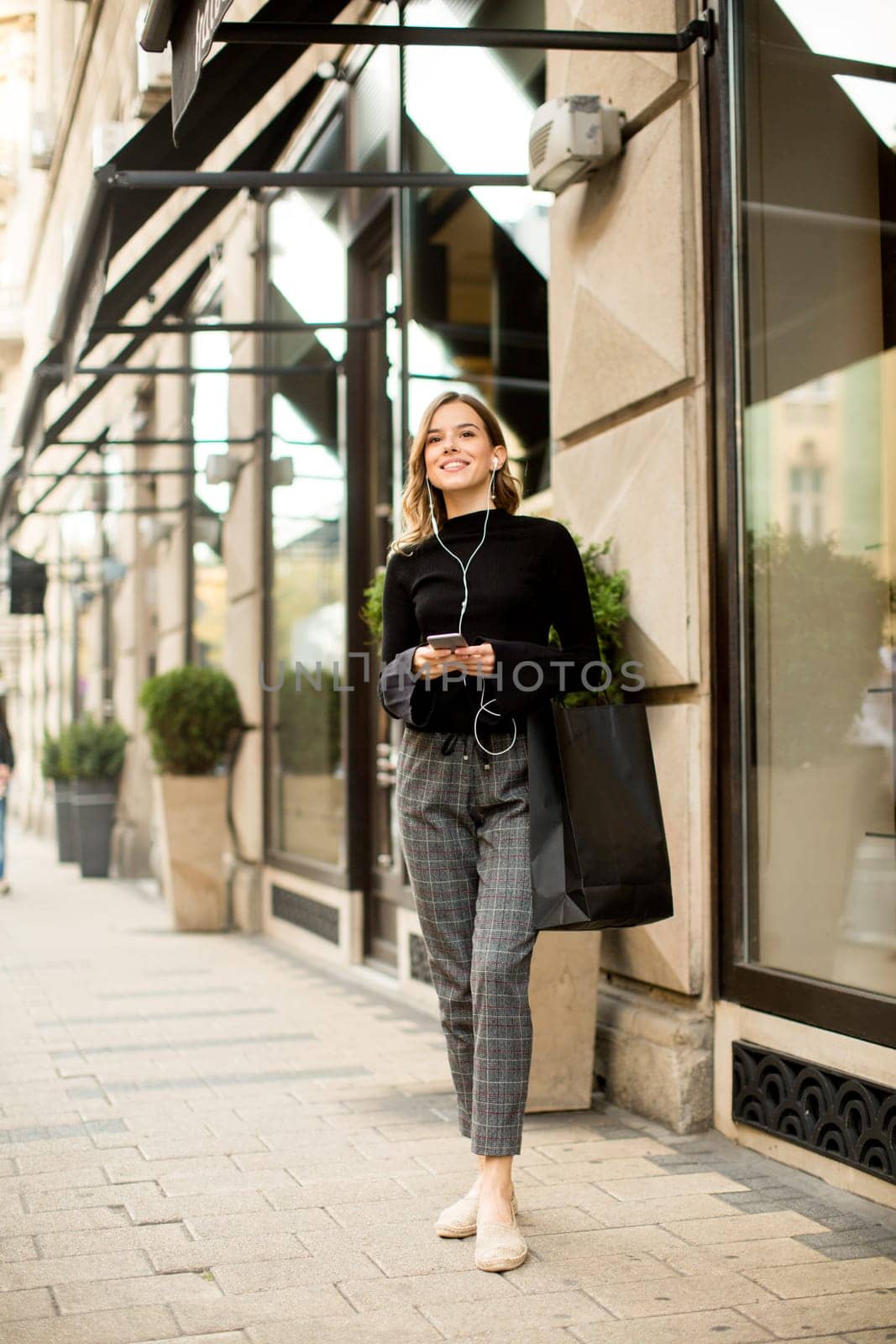 Young woman on the street with mobile phone and listening music