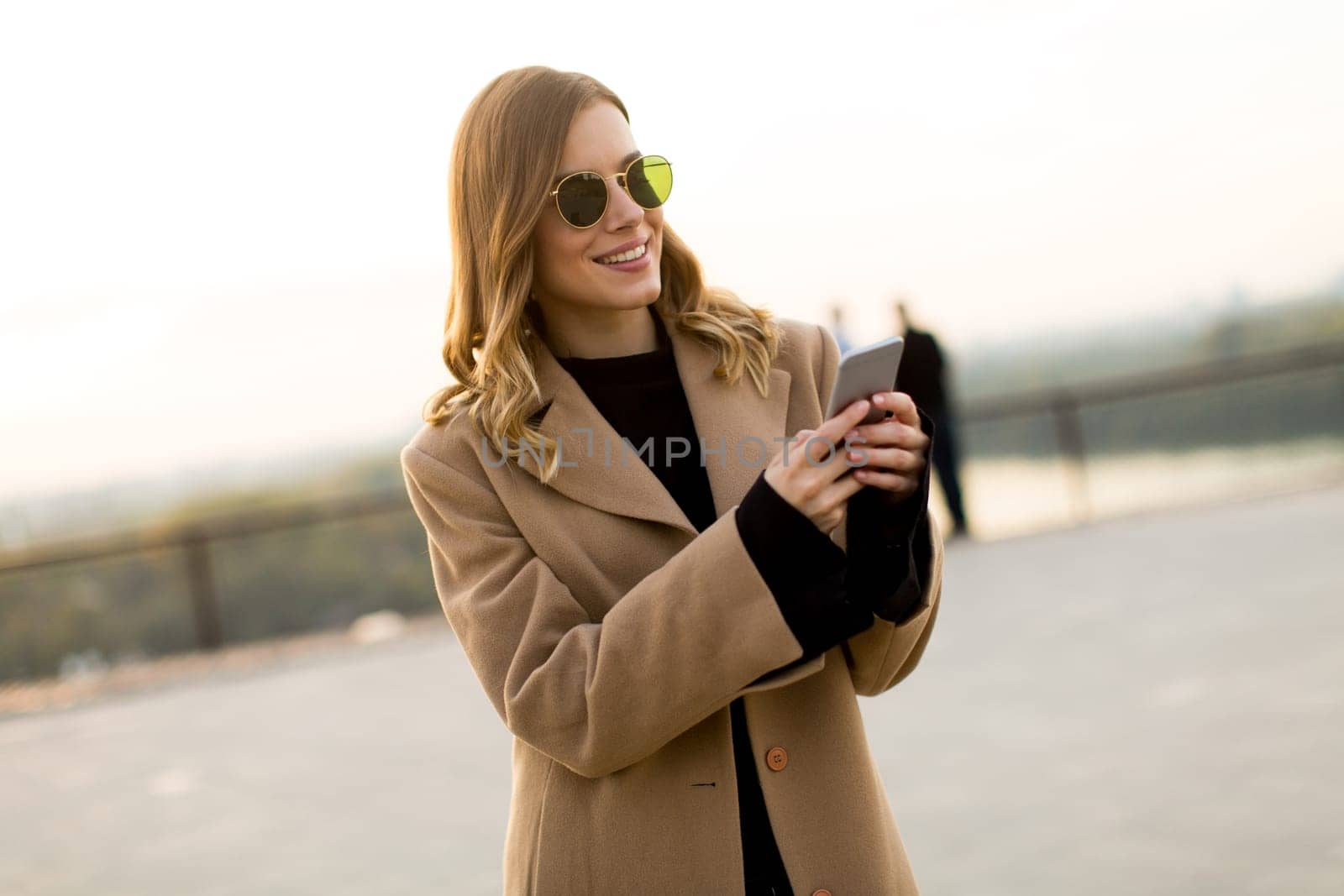 View at modern woman using mobile phone at autumn outdoor