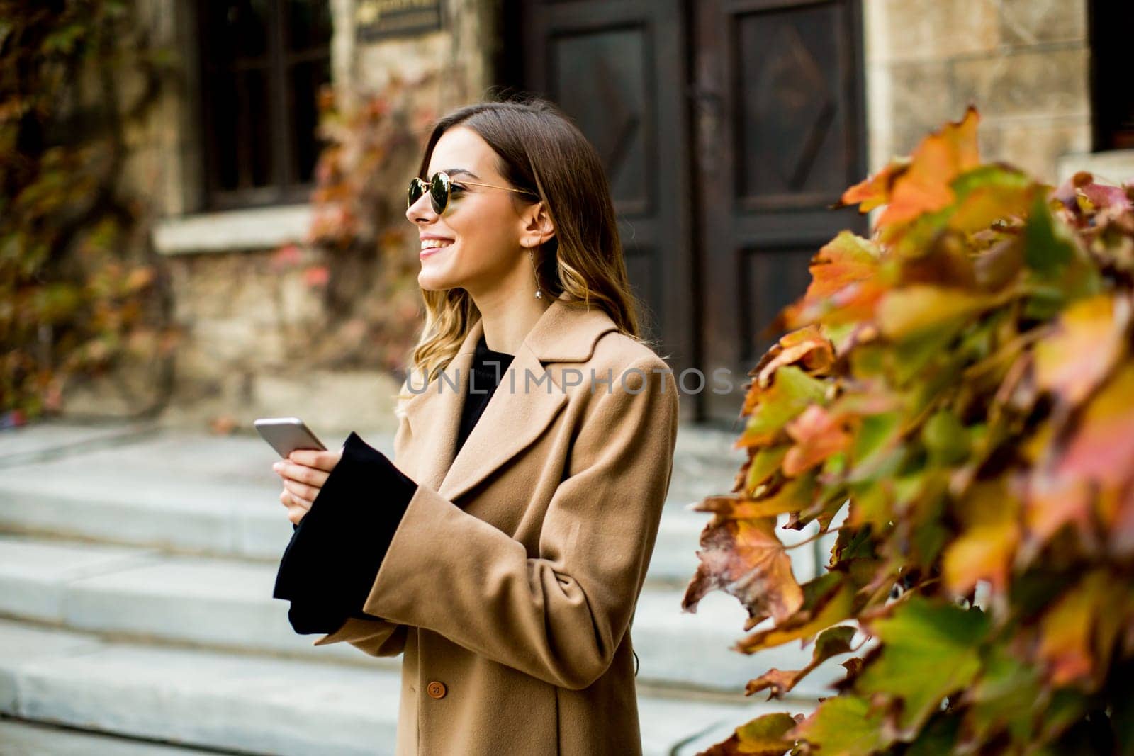 View at modern woman using mobile phone at autumn outdoor