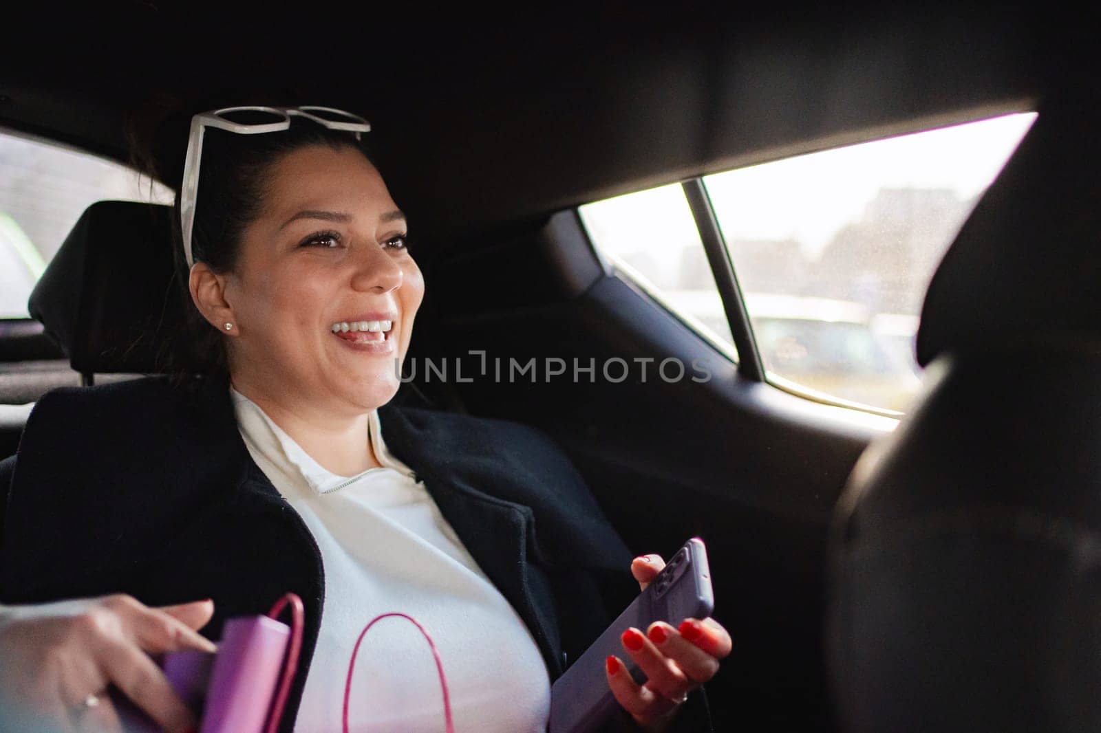 Joyful woman enjoys her time in the car with her phone in hand.