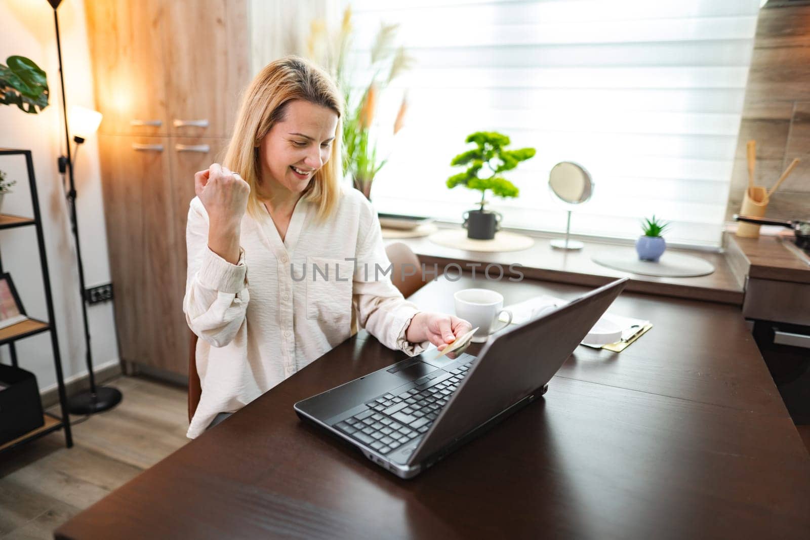 Excited woman beams with joy after achieving a work milestone at home.