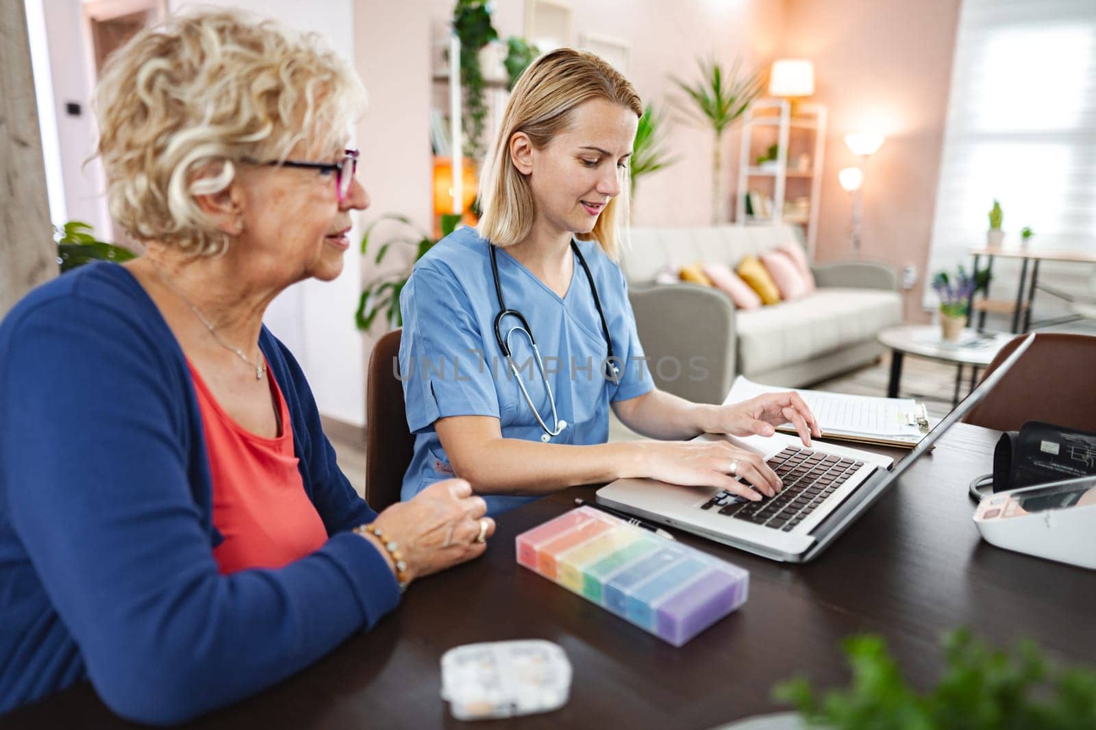A nurse assists a senior woman with health management at home.