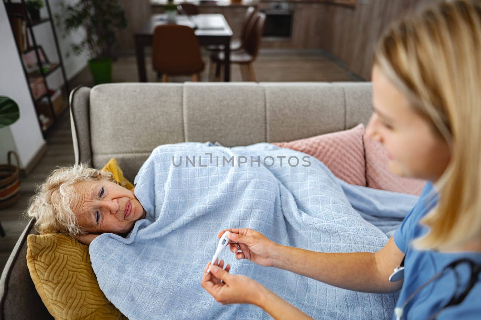 A compassionate caregiver checks on a patient wrapped in a soft blanket.