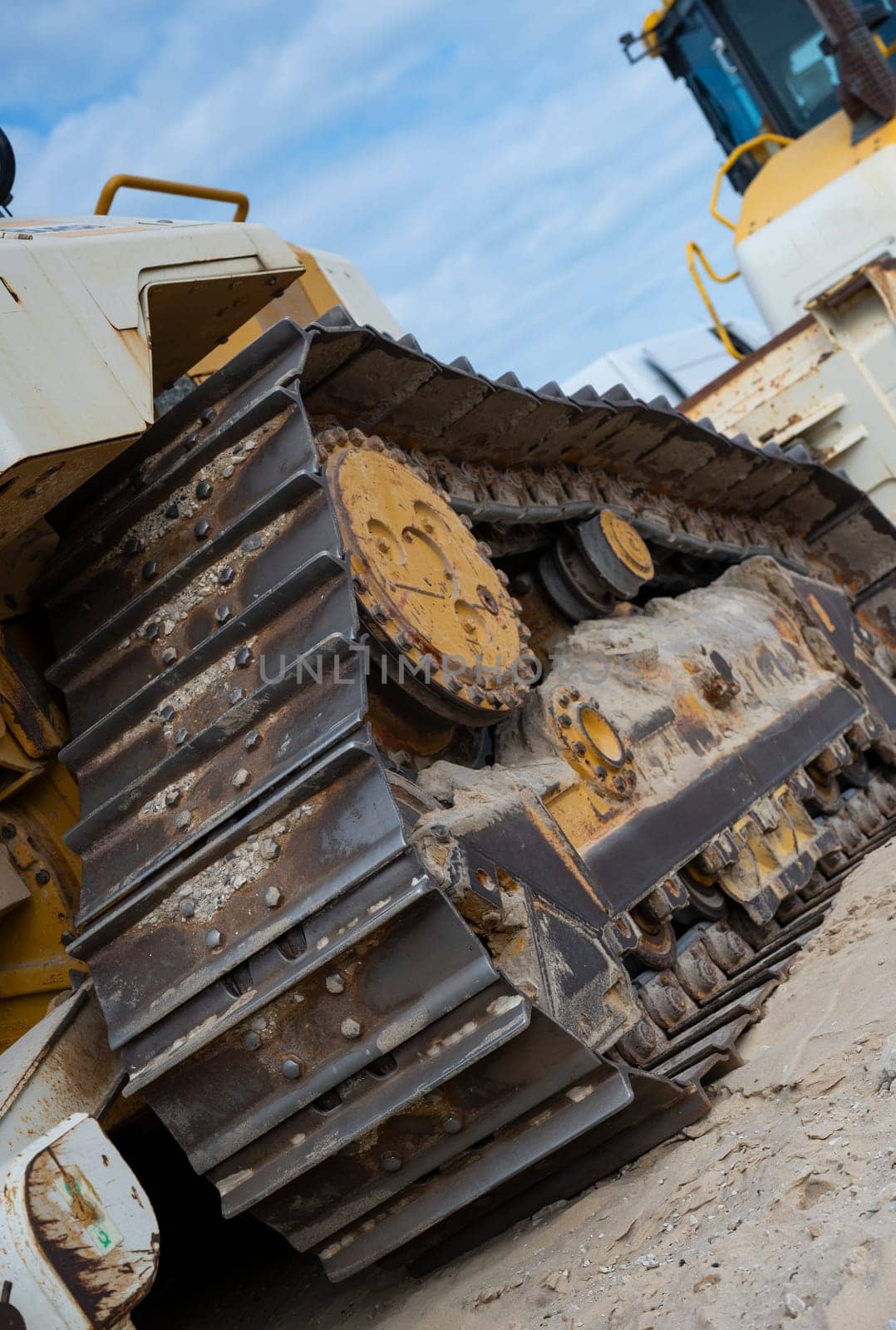Heavy machinery is positioned along the sandy coastline, actively involved in erosion control and coastal protection efforts under a cloudy sky.