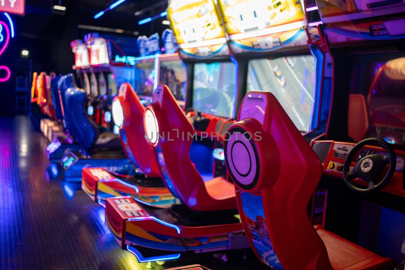 Game Center: Empty red gaming chairs in illuminated arcade game zone. Children's play area in shopping center