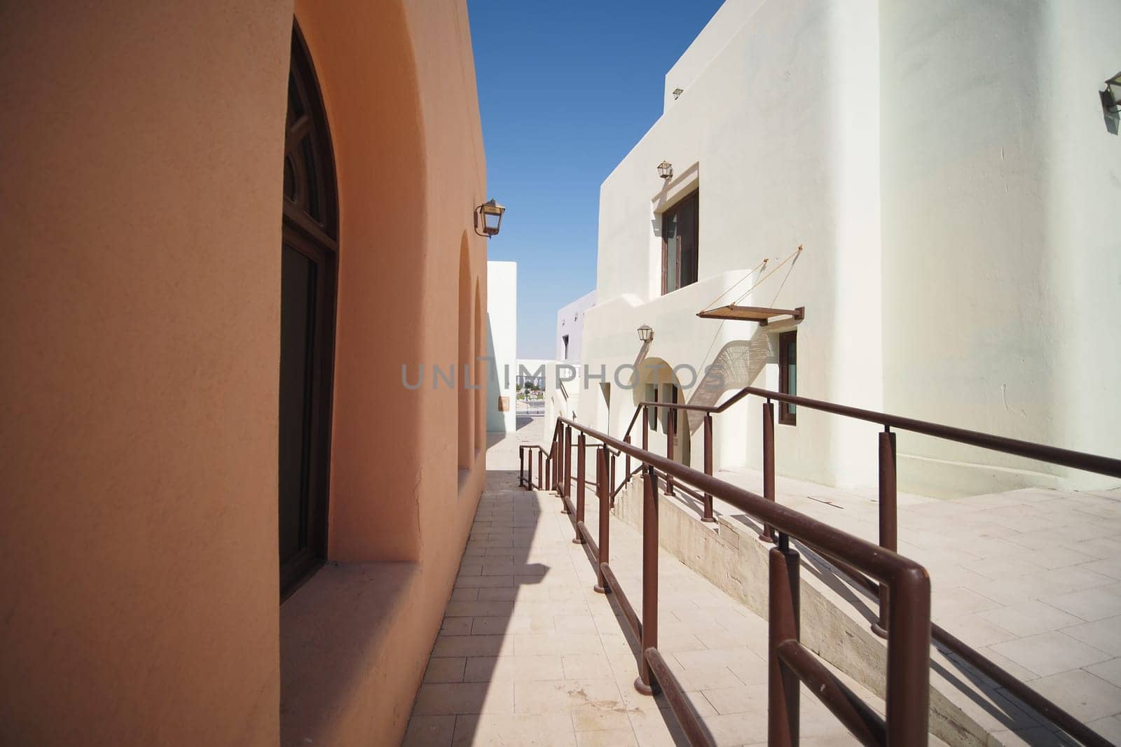 Brightly colored buildings line the pathway in a sunlit town.