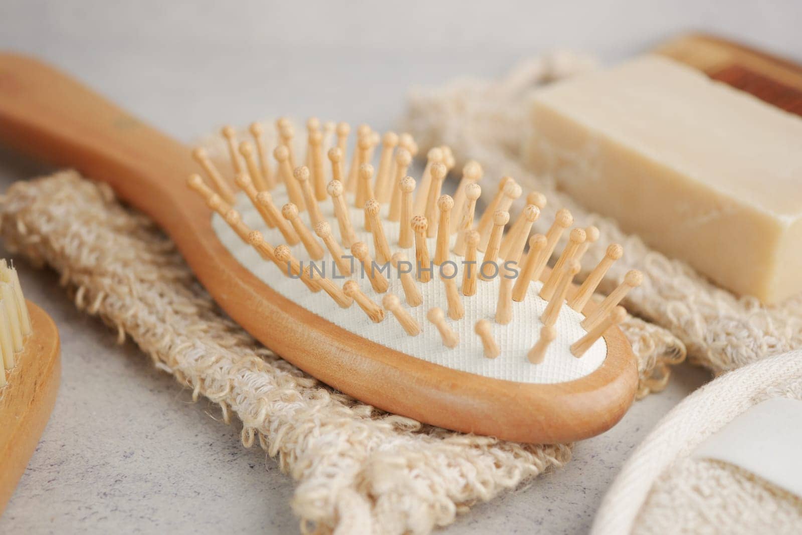 A wooden hairbrush rests on textured fabric with rustic soap nearby.