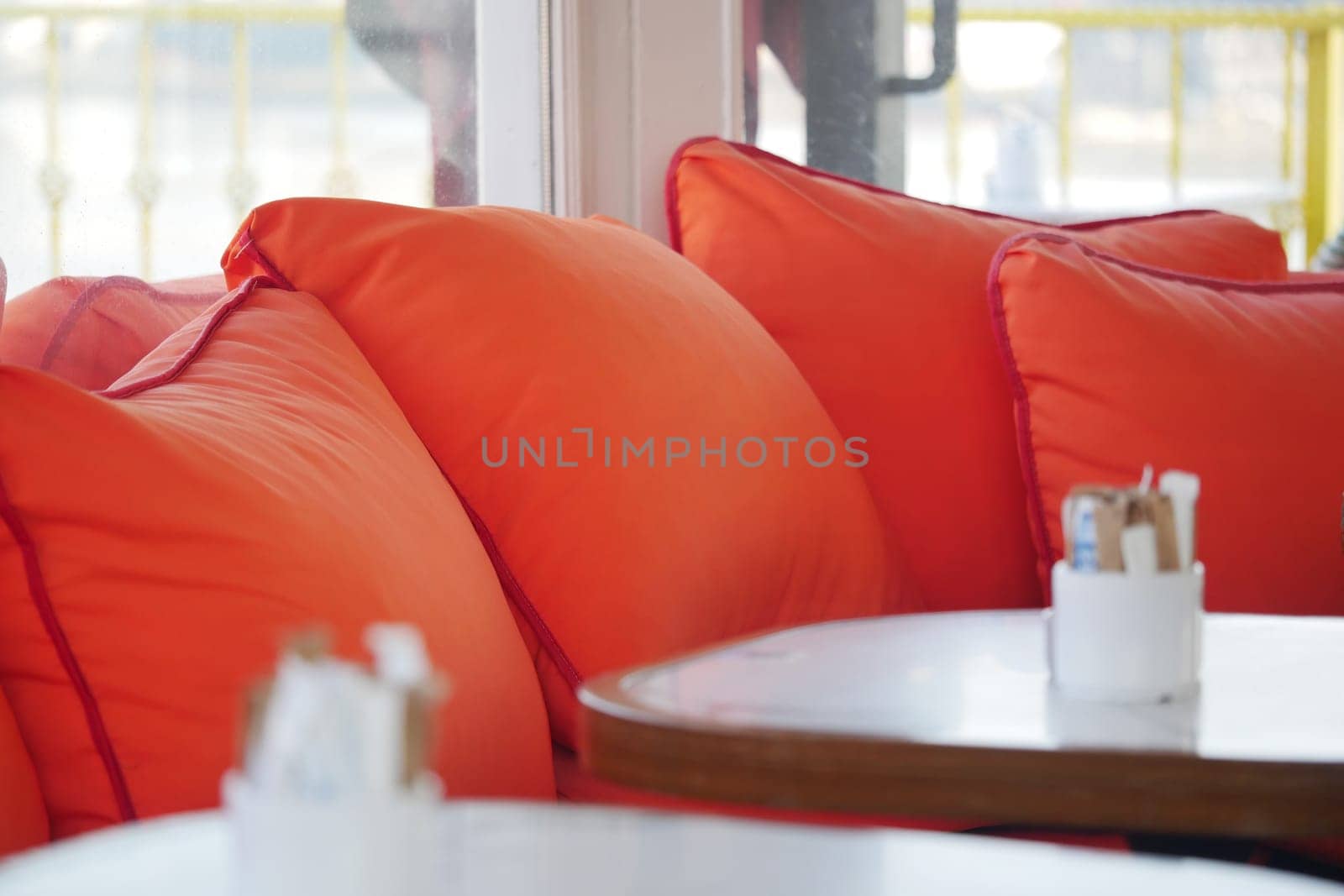 Bright orange cushions adorn the seating in a cozy cafe, inviting relaxation.