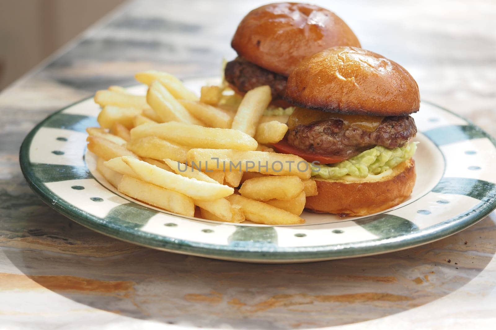 Two stacked cheeseburgers with fries are ready to enjoy for lunch.