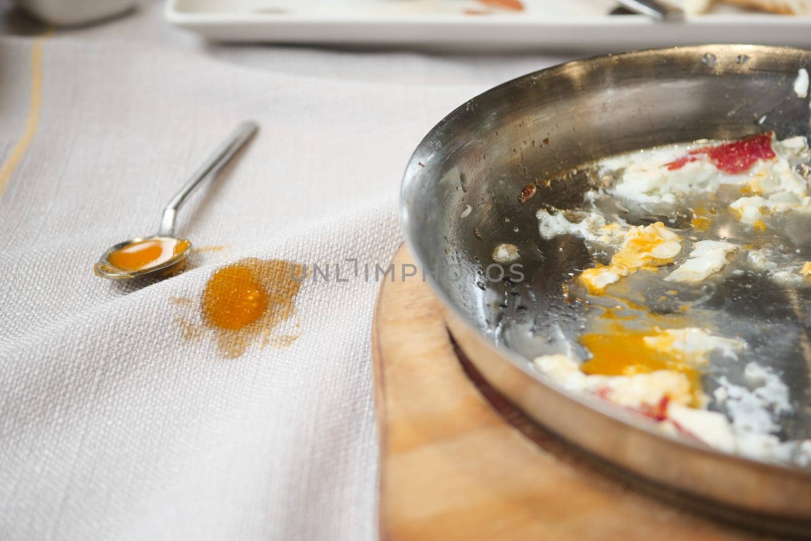 Close-Up of a Food Stain on White Tablecloth Next to Spoon,