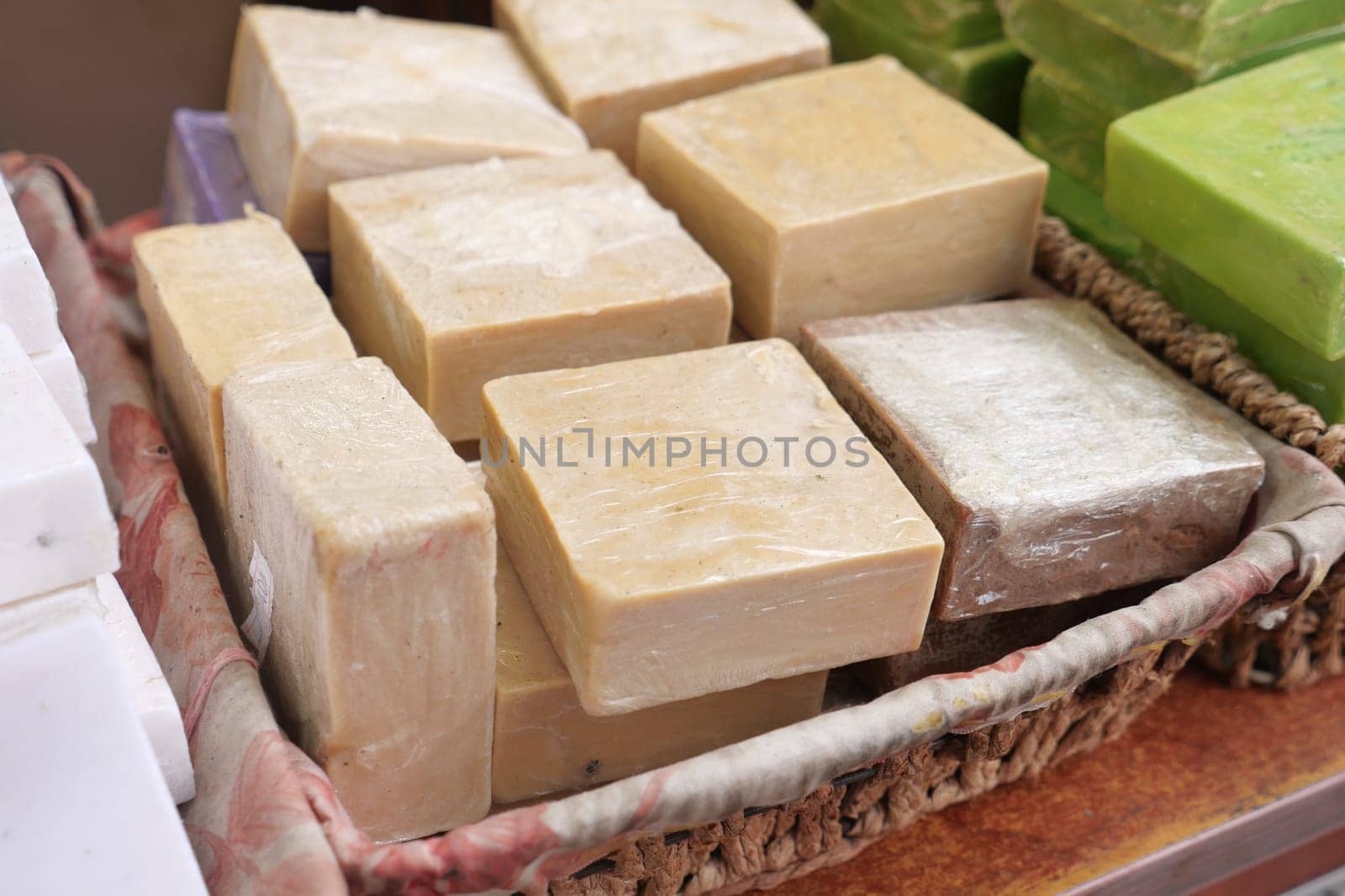 Various handmade soap bars arranged in a woven basket at a local market.