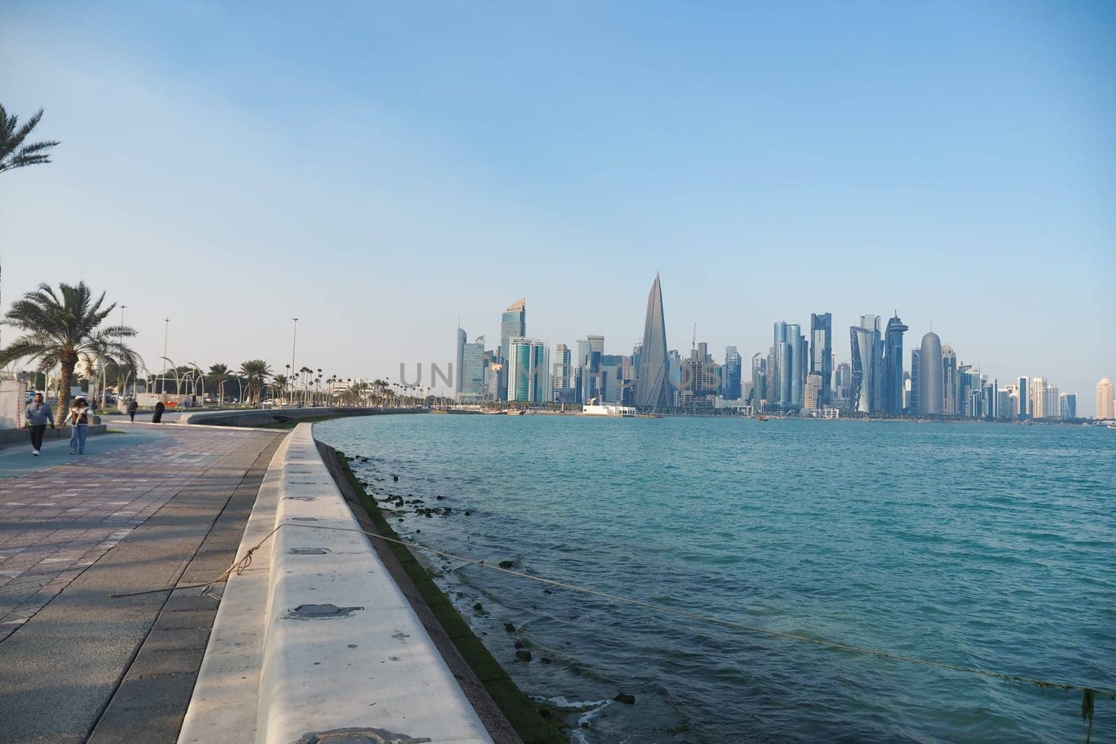 People stroll along the waterfront with stunning city views in Qatar.