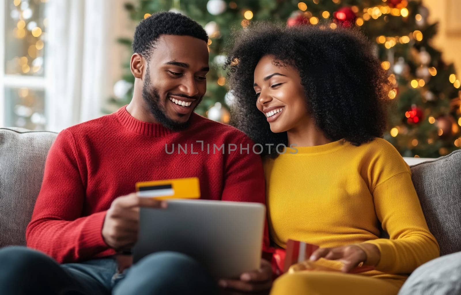 A couple sits close on the couch, smiling and engaged in online shopping, with festive Christmas decorations in the background.
