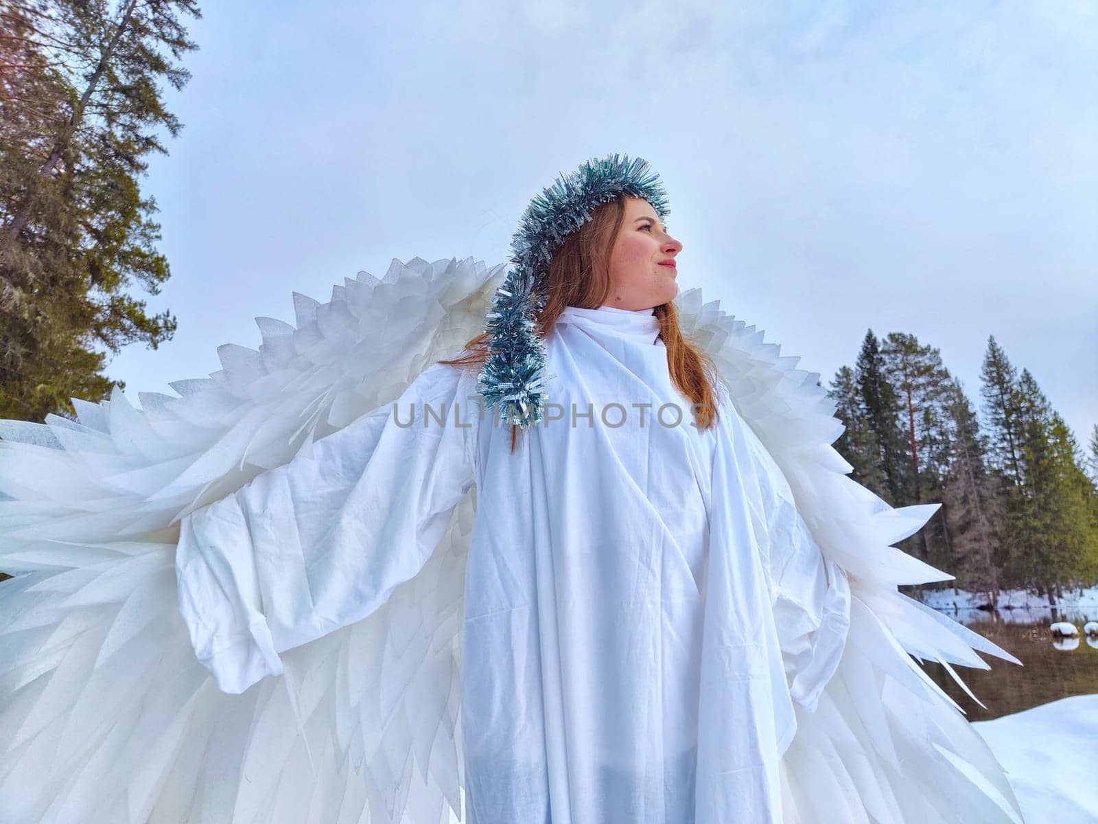 Young girls in flowing white dresses pose gracefully by a tranquil lake, embodying winter fairies amidst the changing seasons.