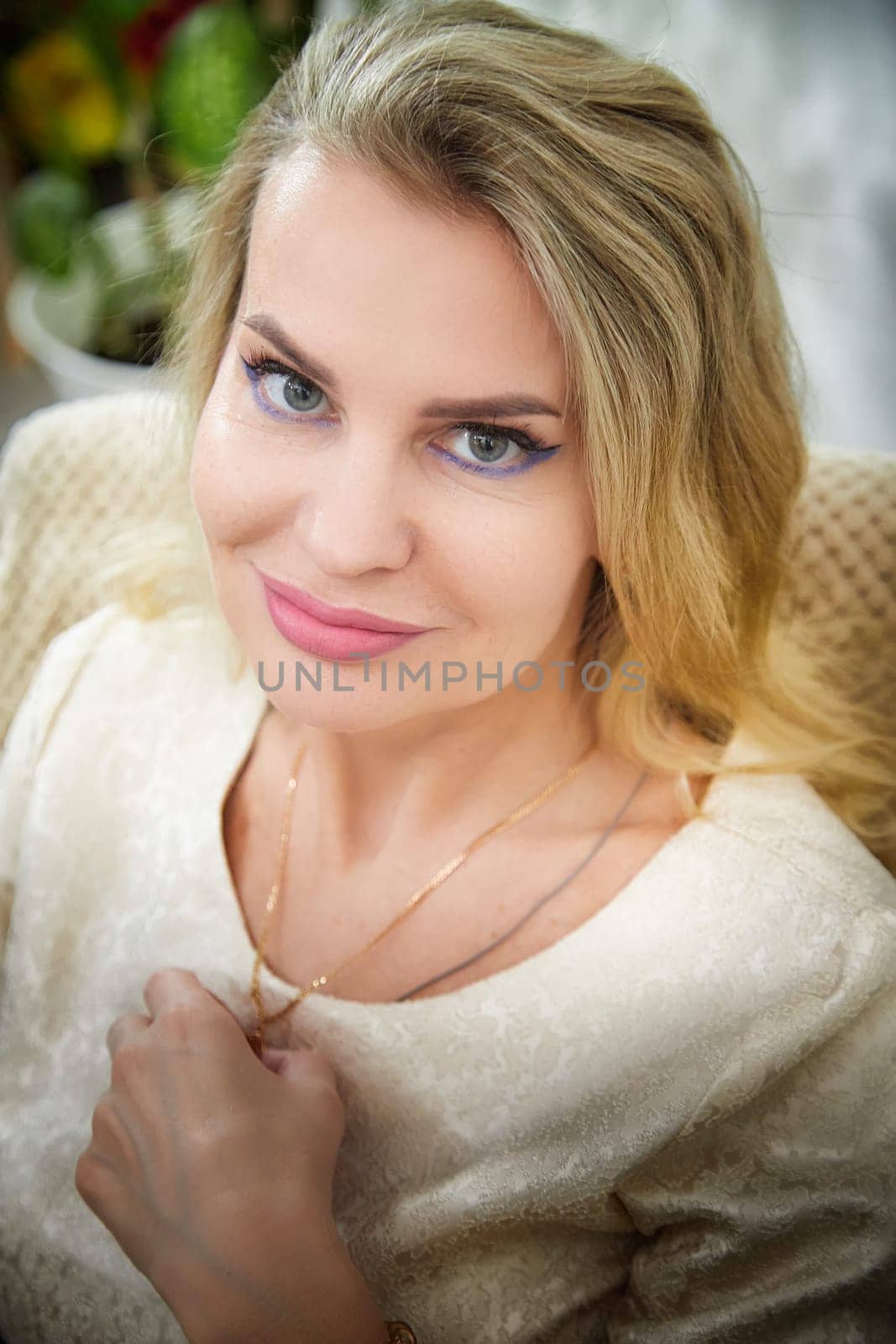 A mature woman showcases her blogging lifestyle with a warm smile and stylish pose in her cozy home setting.