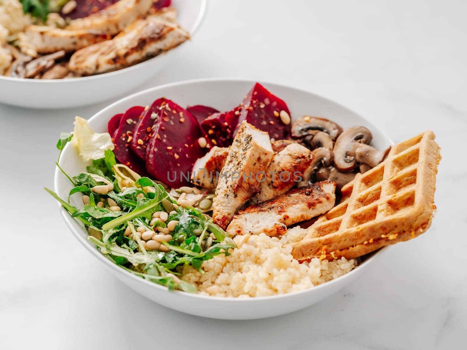 Bowl with grilled chicken, mushrooms, beetroot, quinoa, green rucola, decorated pine nuts and carrot waffle. Top view of gourmet bowl. Balanced gourmet dish on black wooden background. Healthy Food