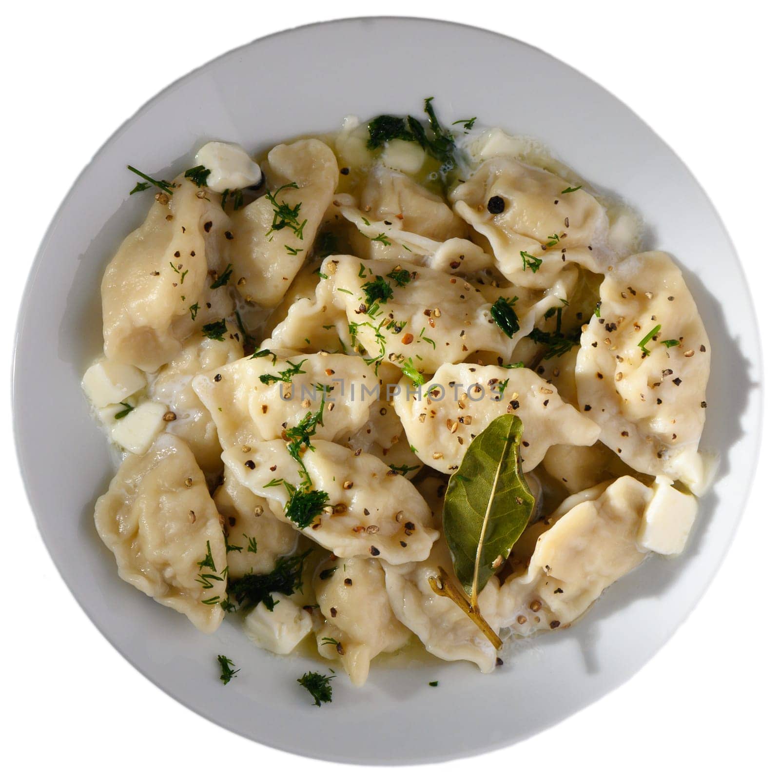 Freshly made dumplings sit in a white bowl, garnished with herbs and spices, ready to be enjoyed.