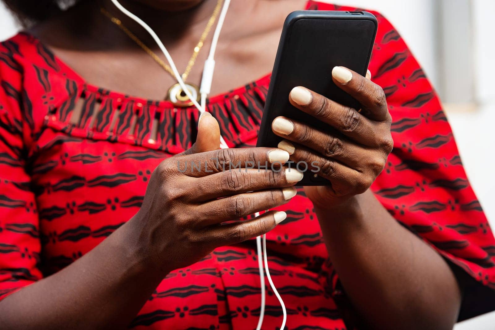 close up of woman hands in red outfit holding cell phone with earphone