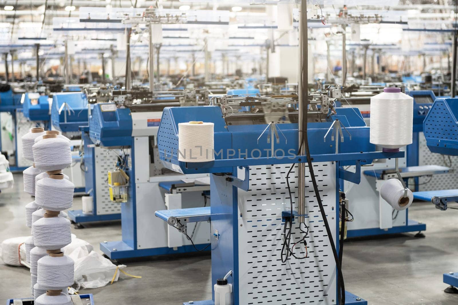 View of automated textile manufacturing machines in a factory, with spools of white thread ready for processing.