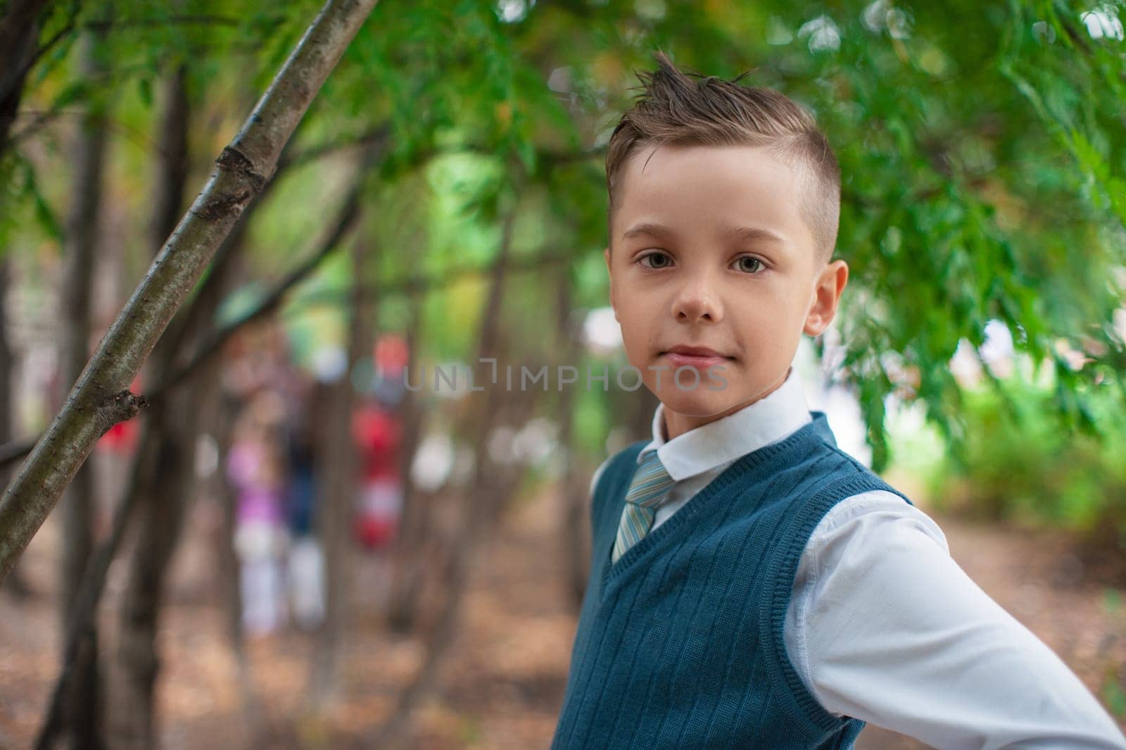 A young pupil boy in stylish clothing holds a bouquet of red and yellow flowers, on September 1 for Knowledge Day, the beginning of the school year