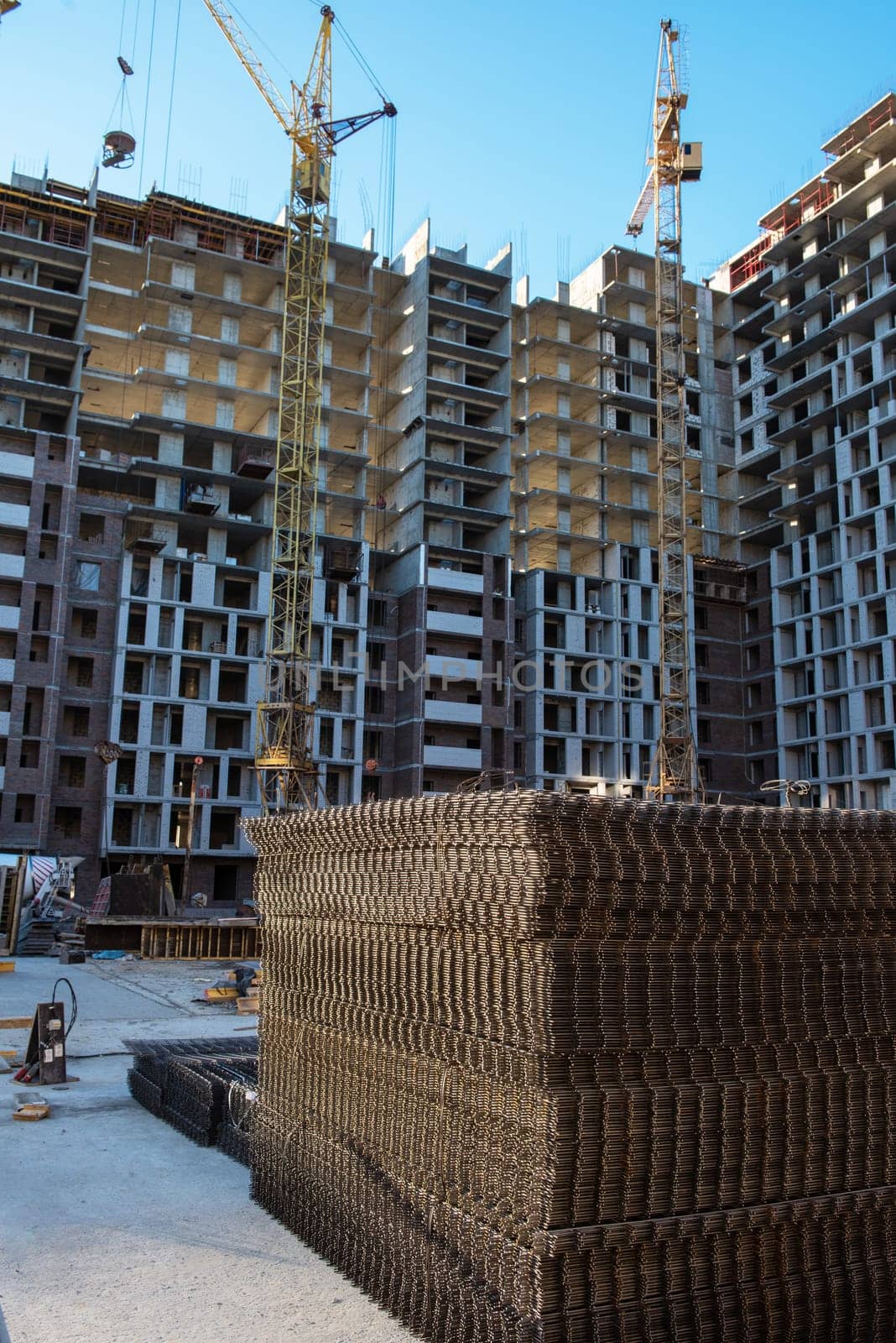 Ongoing construction of modern high-rise apartments with cranes, steel reinforcements, and unfinished structures.
