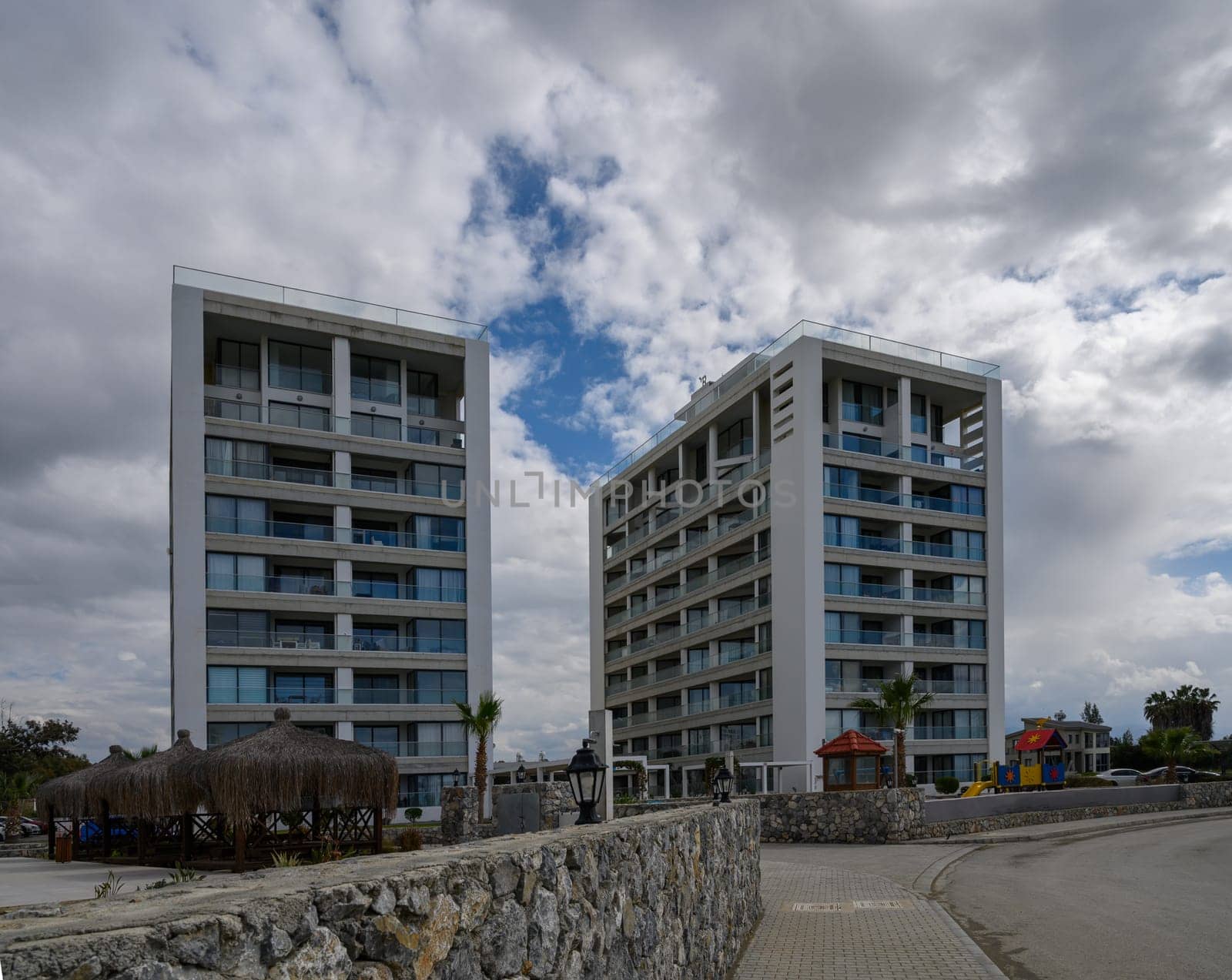 Sleek structures rise above rocky terrain, embraced by lush greenery and clouds, signaling modern living.