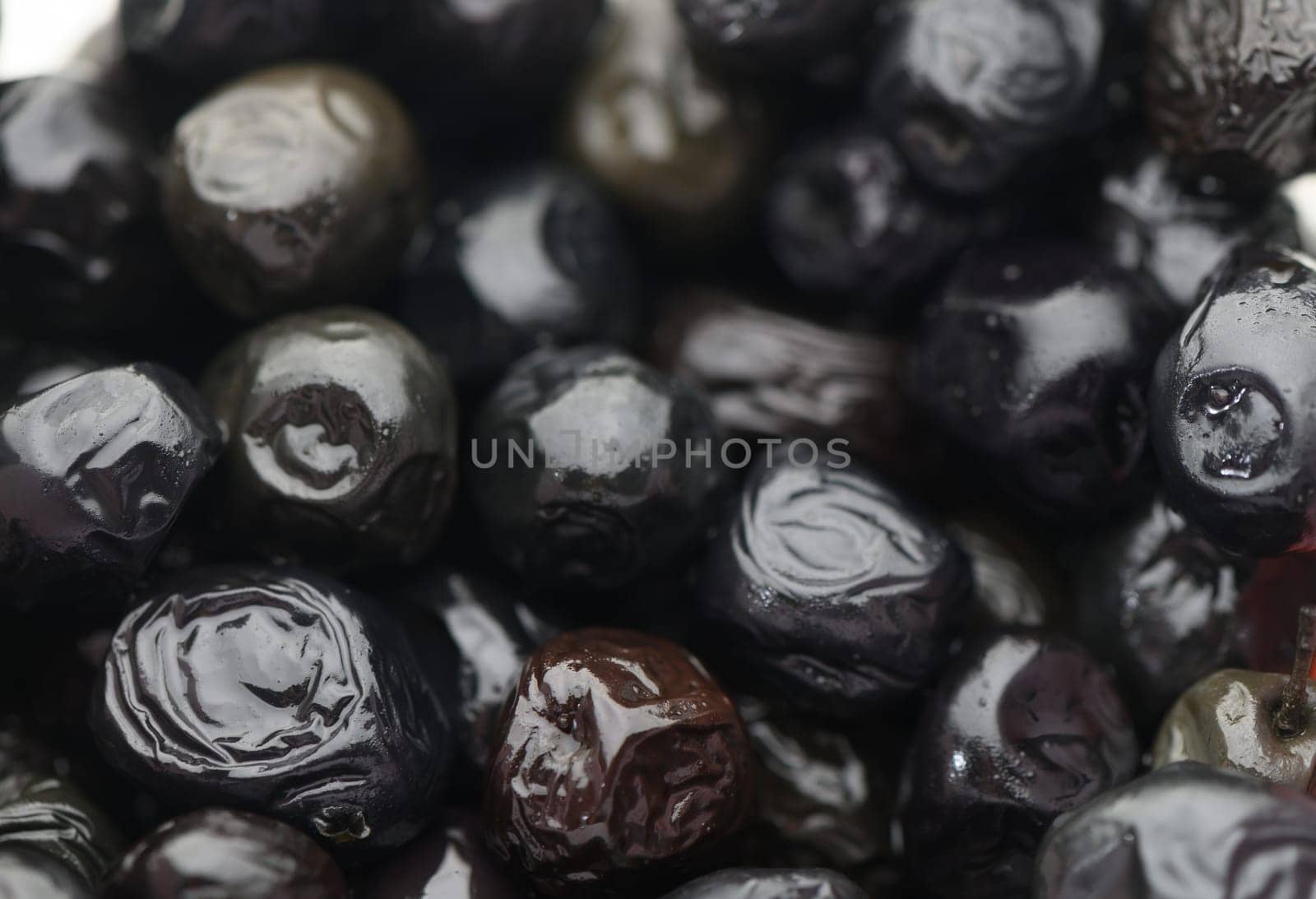 Black olives glisten with dew, showcasing their rich texture and vibrant color after being picked at dawn.