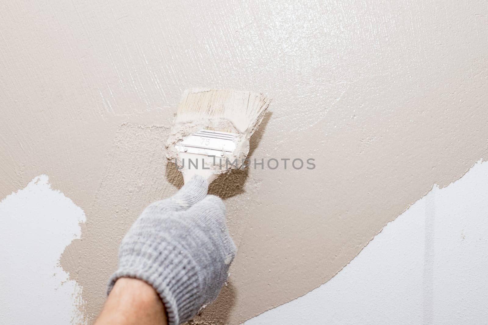 Closeup man hand in purple rubber glove with paintbrush painting natural wooden door with yellow paint, creative design house renovation theme.