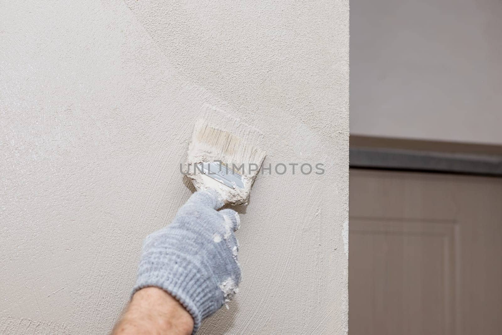Closeup man hand in purple rubber glove with paintbrush painting natural wooden door with yellow paint, creative design house renovation theme.